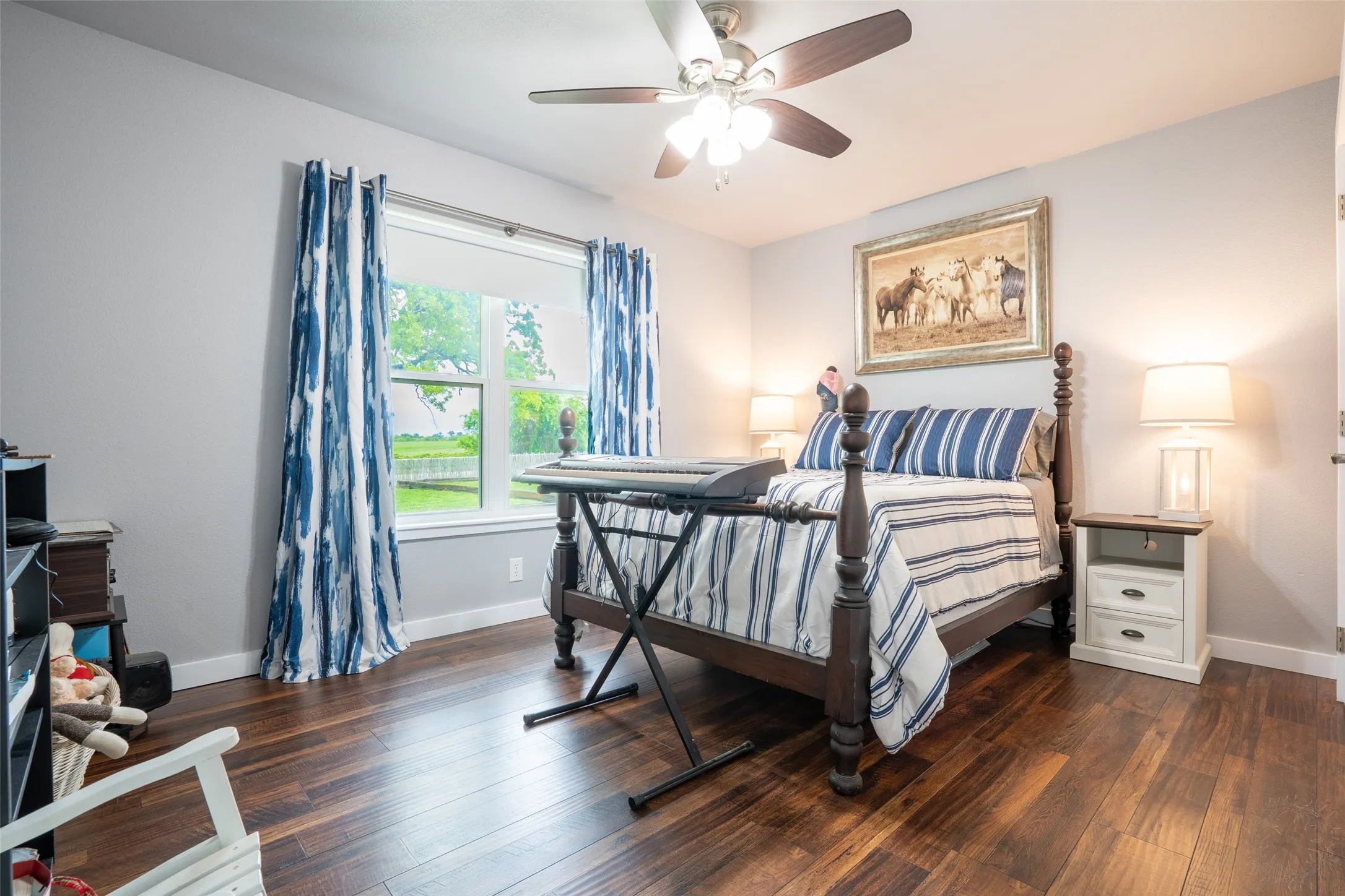Interior room featuring wood-finish flooring, a window offering views of greenery, and a ceiling fan with integrated lighting
