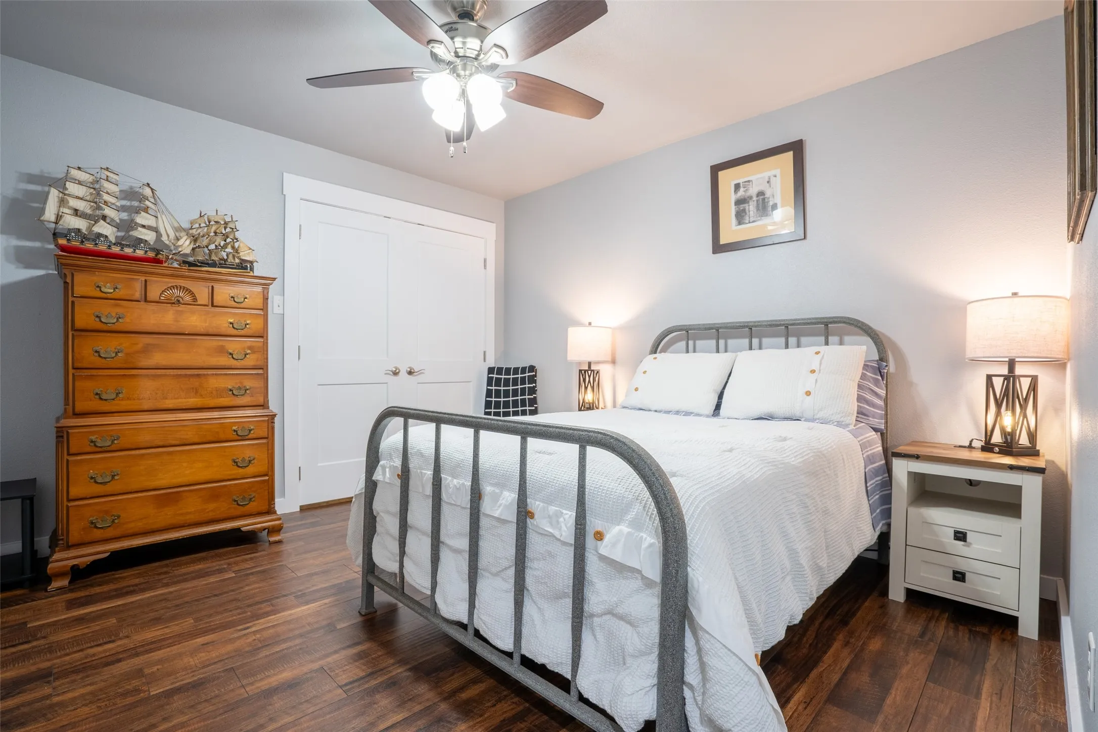 Bedroom featuring wood-finish flooring, a ceiling fan with integrated lighting, and white bi-fold closet doors