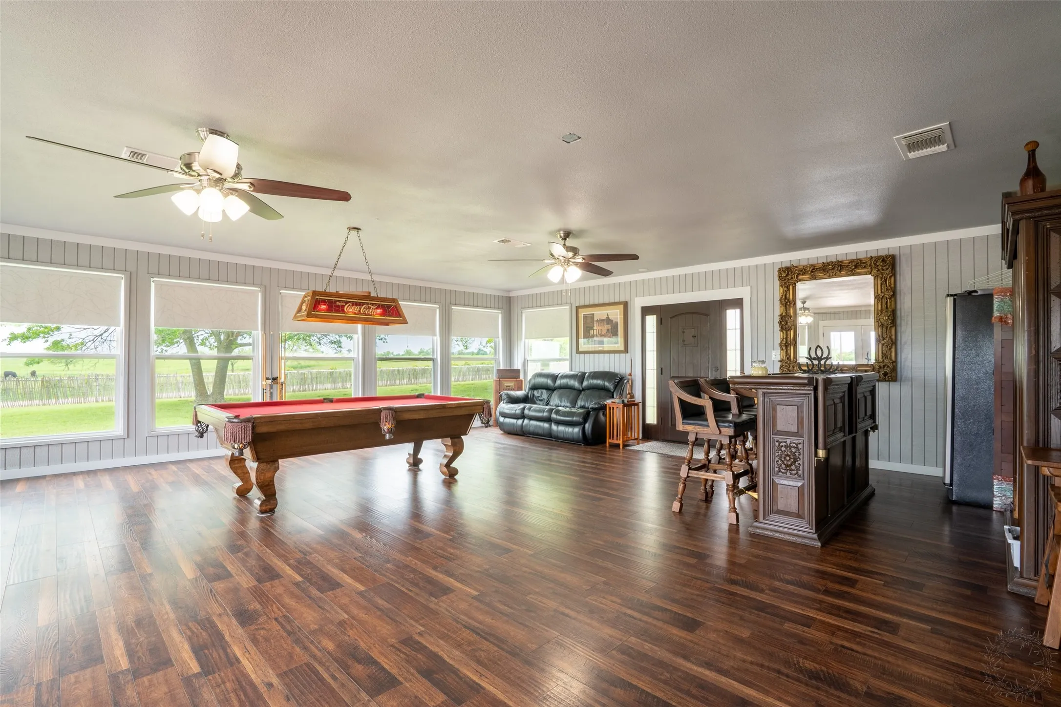 Spacious game room featuring wood-finish flooring, a series of large windows, and beadboard wall paneling