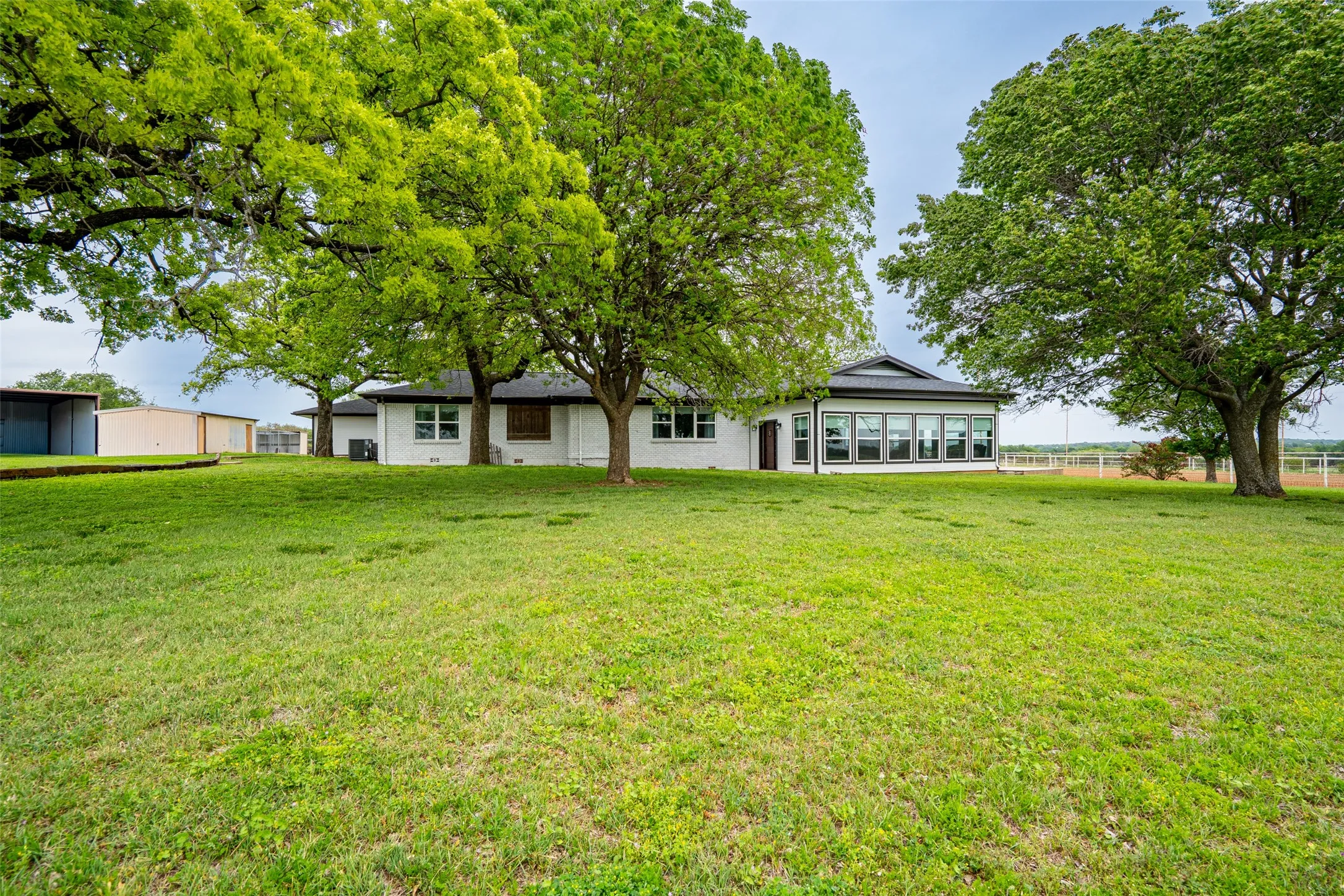 Expansive green lawn surrounding a white-painted brick exterior with a dark-pitched roof