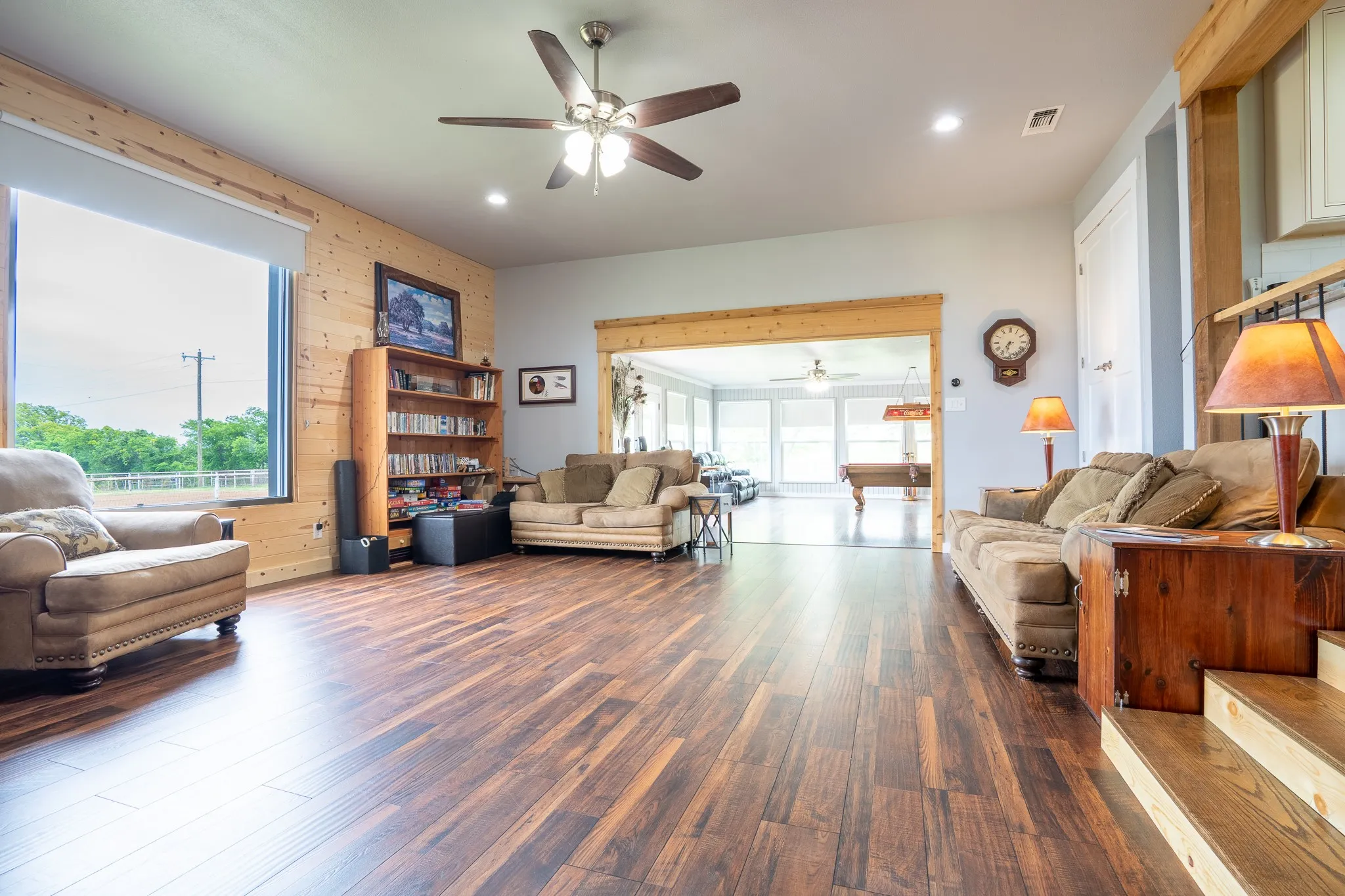 Spacious interior featuring wood-finish flooring, a ceiling fan with integrated lighting, recessed lighting, and a large picture window