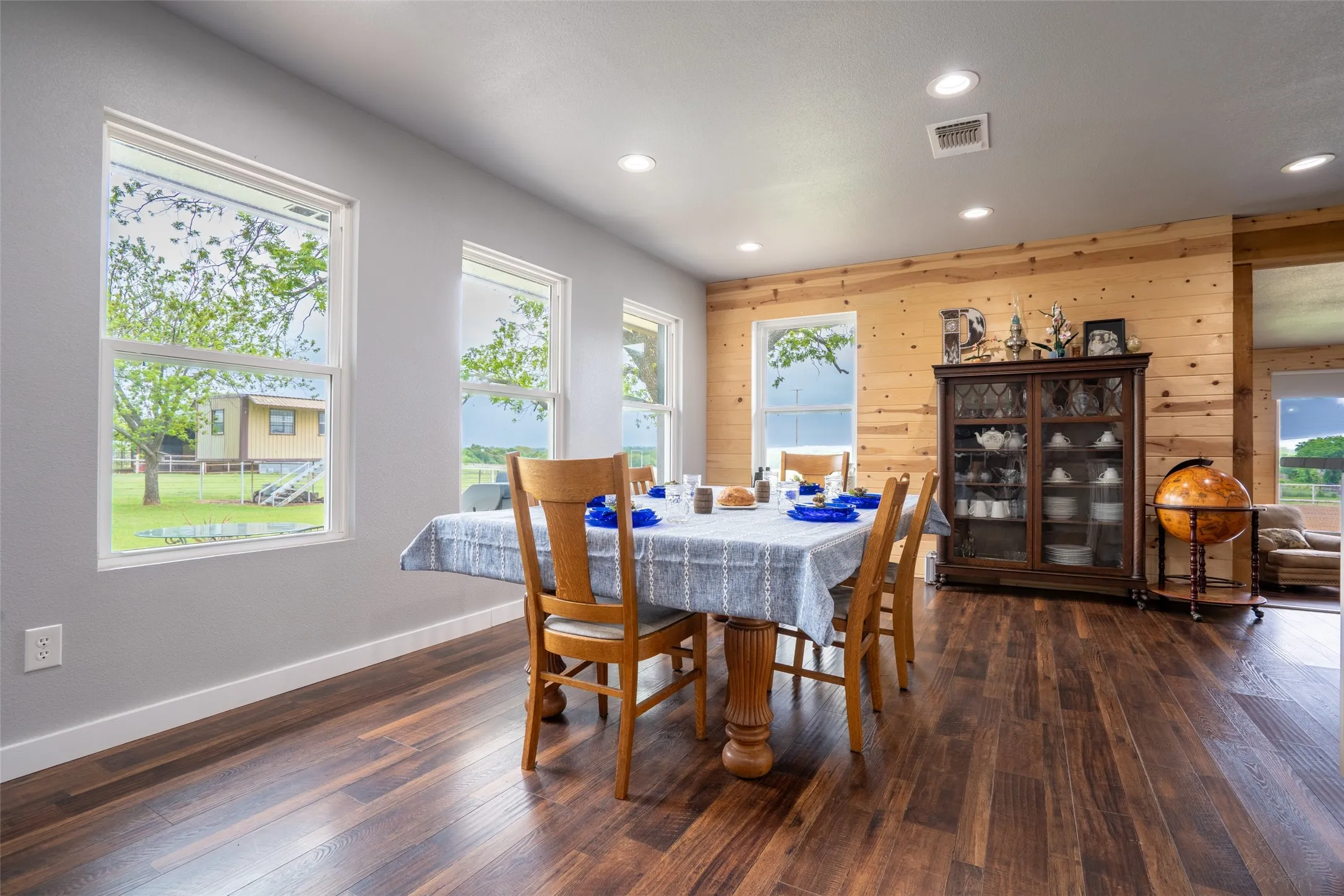 Dining area featuring wood-finish flooring, recessed lighting, and a feature wall with natural wood paneling