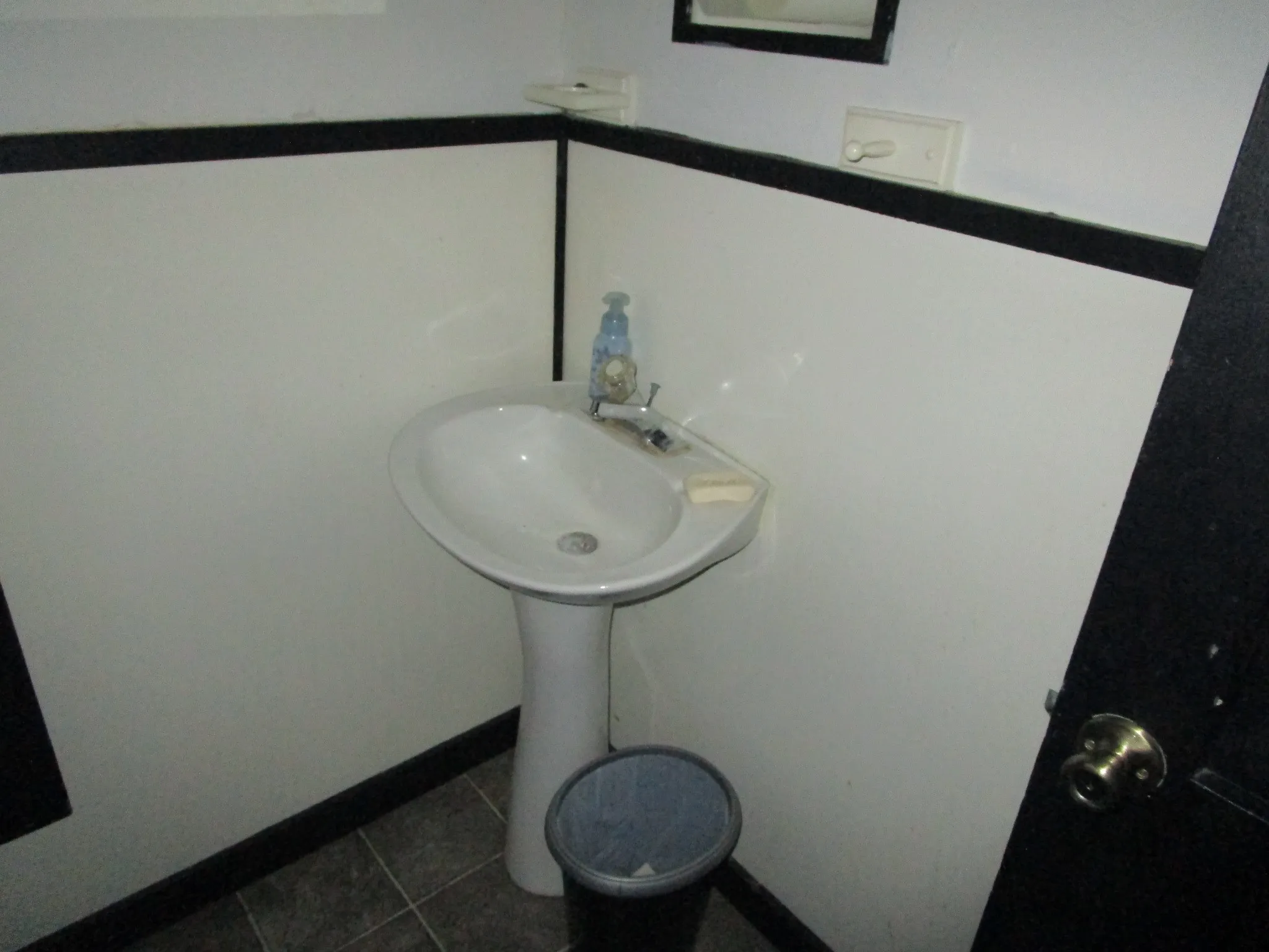 Pedestal sink with chrome faucet set against a two-tone wall and tile flooring