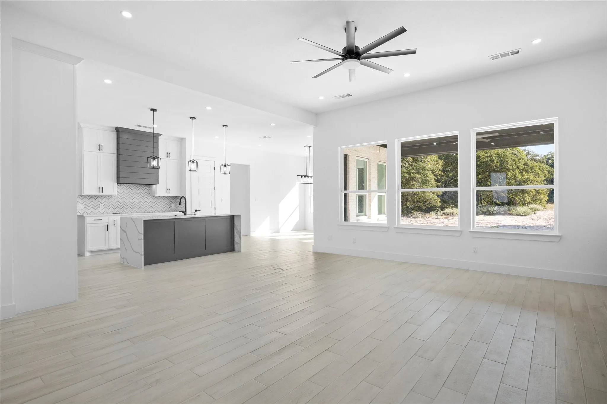Open-concept interior featuring light Porcelain Tile-finish flooring, recessed lighting, and a contemporary ceiling fan. Well lighted Living room, Kitchen and Dining area