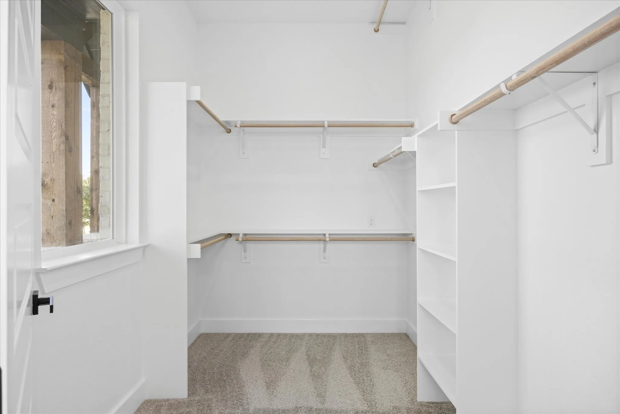 Walk-in Master closet featuring built-in shelving, multiple hanging rods, and neutral carpet flooring