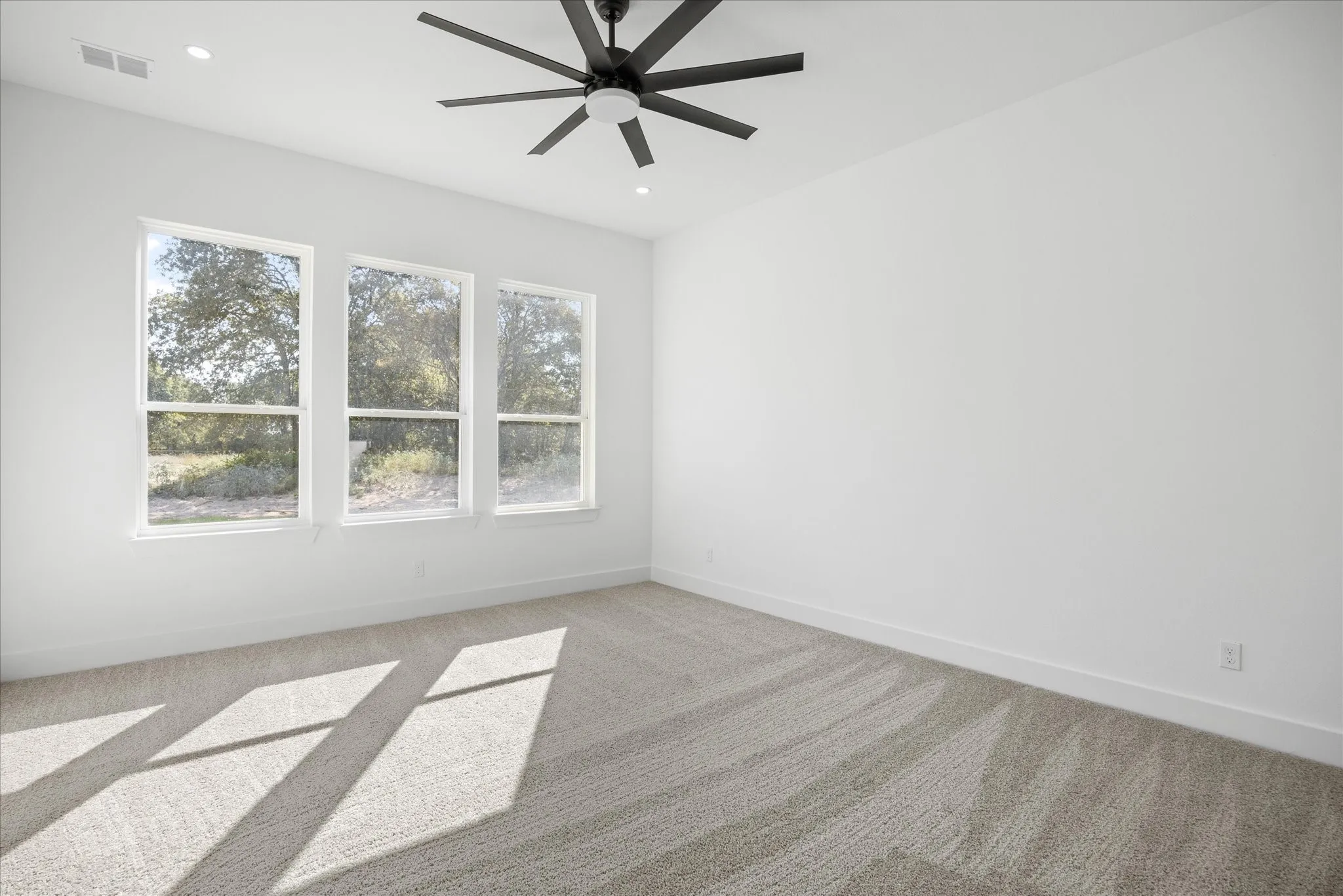 Spacious Owners room featuring three large windows, recessed lighting, and a modern black ceiling fan