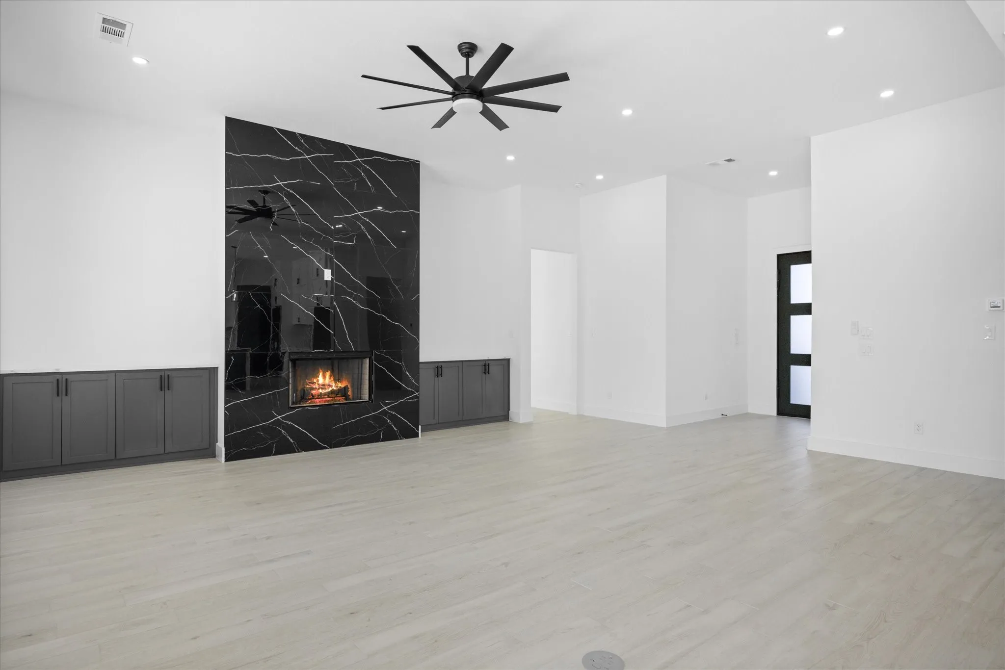 Spacious living area featuring a dramatic black and white veined fireplace, light Wood looking grey Porcelain Tile-finish flooring, recessed lighting, and a modern ceiling fan