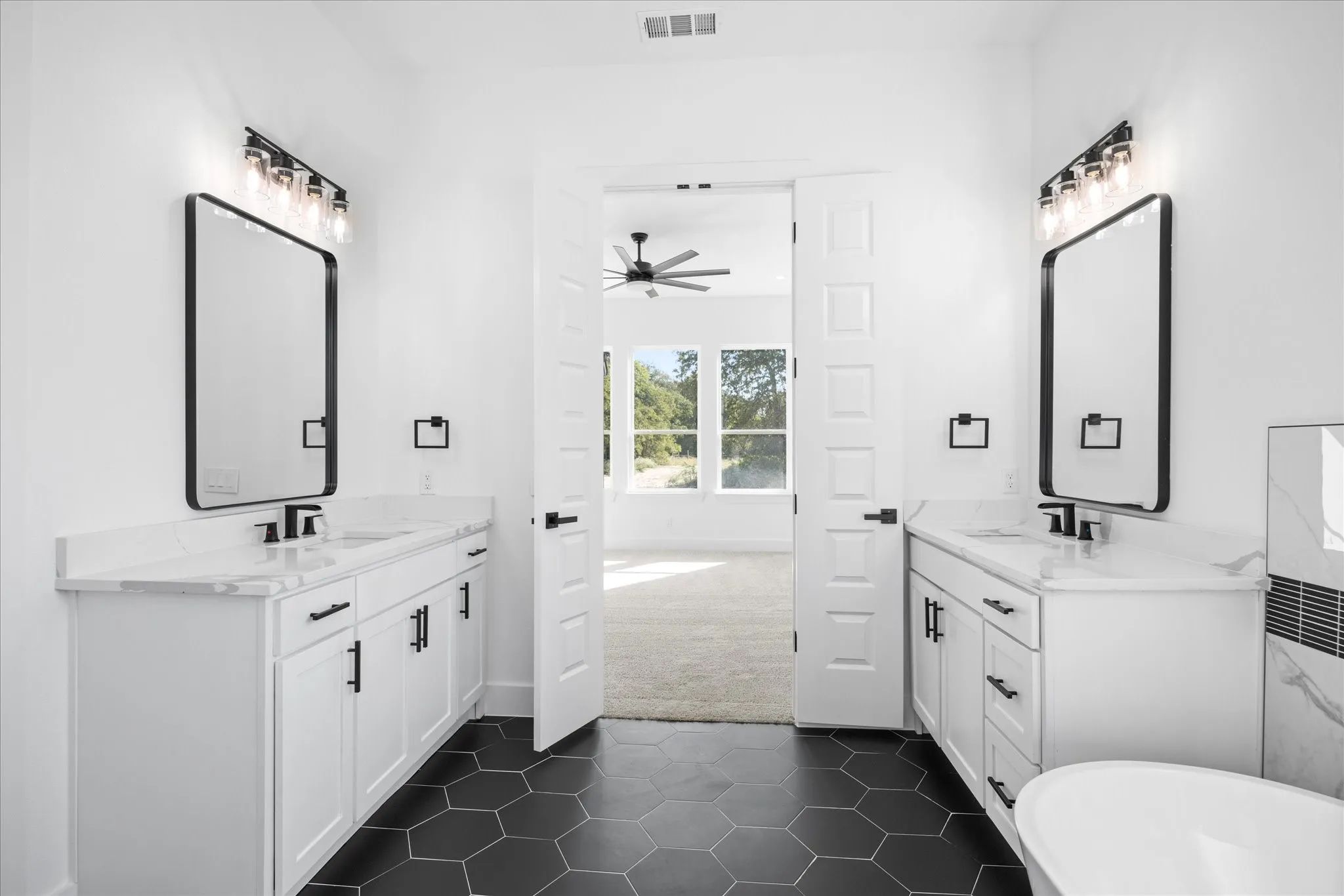 Dual vanities with white cabinetry, black hardware, and stone countertops