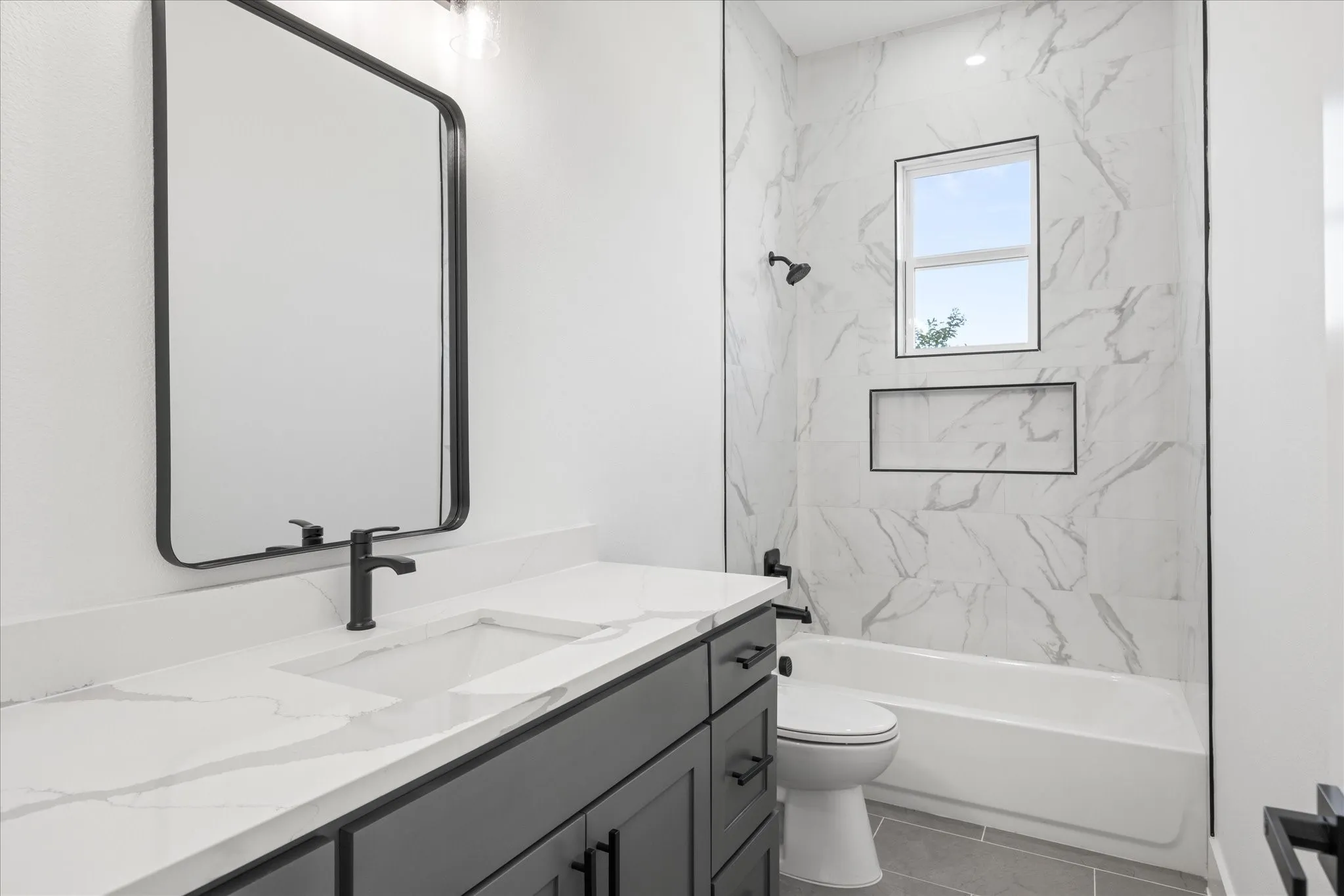 Contemporary Kids/Guest bathroom featuring a dark vanity with a white countertop, an integrated rectangular sink, and matte black fixtures