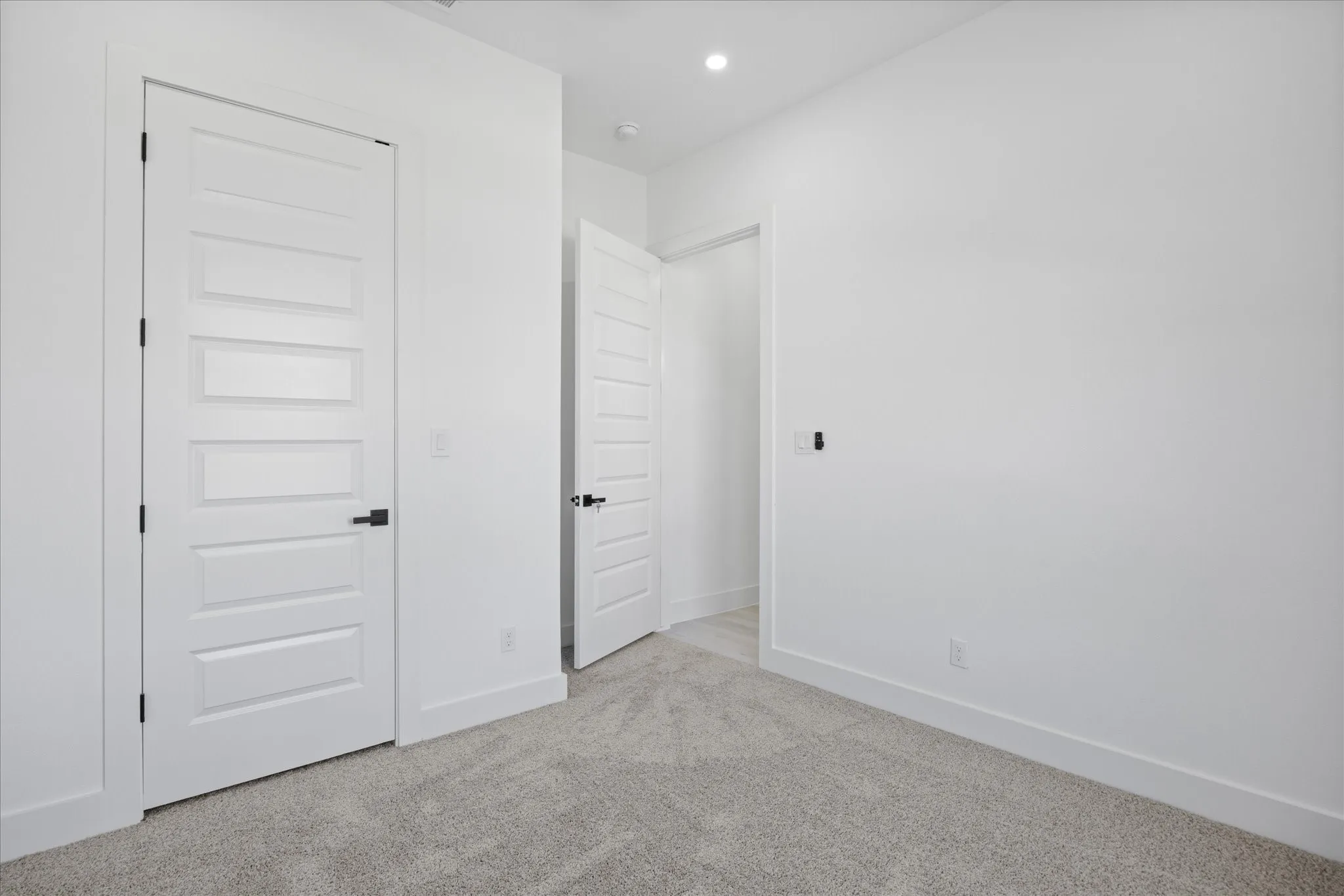 Kids/Guest bedroom featuring light gray carpeting, crisp white walls, recessed lighting, and modern five-panel doors with matte black hardware