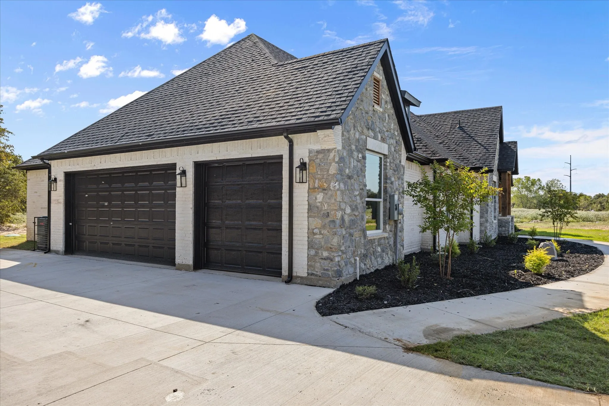 3-car Garage- Stone and brick exterior with a dark shingle roof