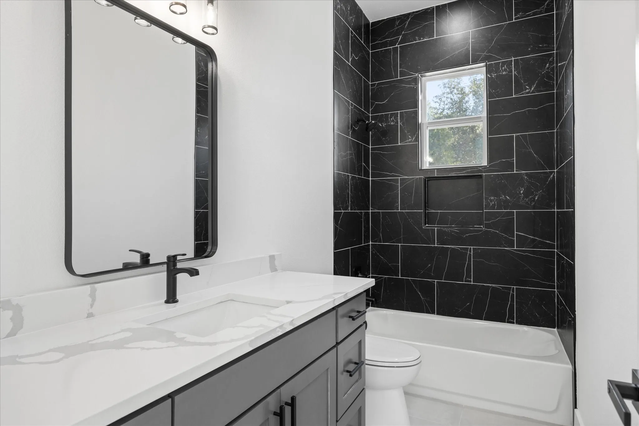 Kids Full Bathroom featuring a single vanity with a white countertop and integrated sink, matte black faucet, and a large framed mirror