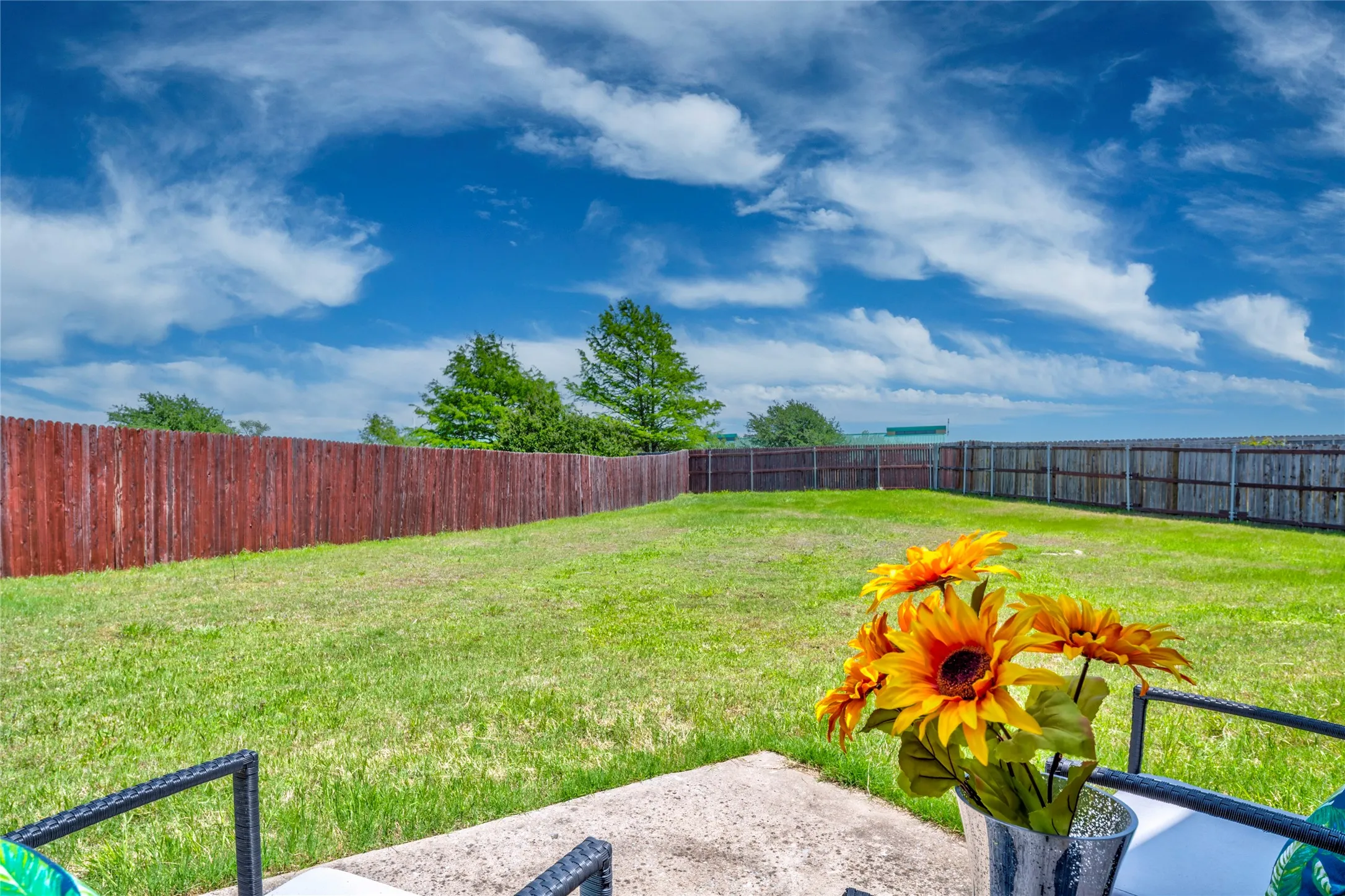 Expansive backyard featuring a full perimeter wood privacy fencing, and a concrete patio area
