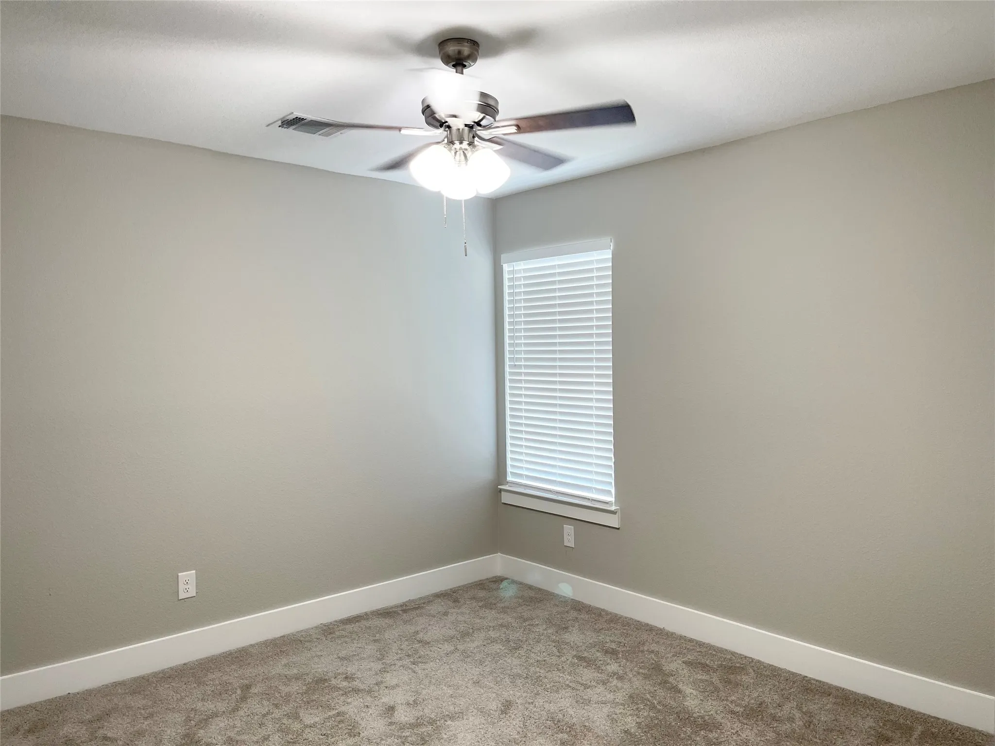Carpeted room featuring a ceiling fan with integrated lighting, a window with horizontal blinds, and baseboard trim