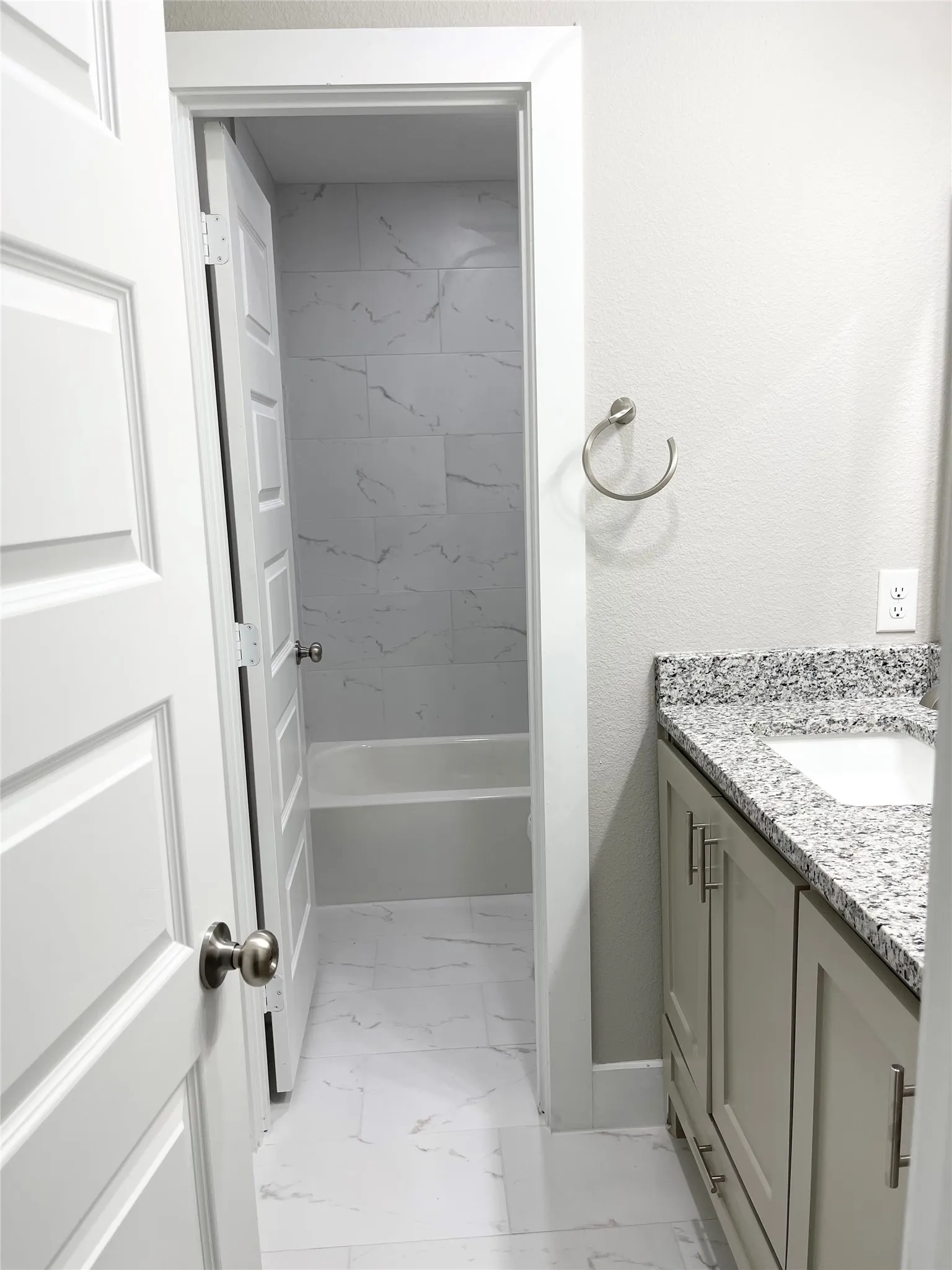 Bathroom vanity featuring light cabinetry and a granite-style countertop with an undermount sink