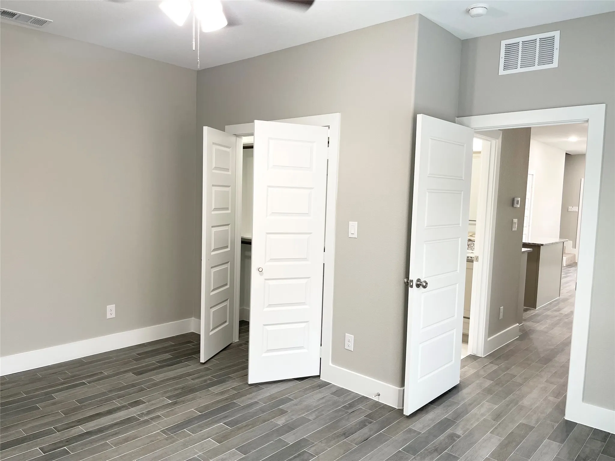 Spacious room featuring modern wood-finish plank tile flooring, neutral wall paint, and white trim