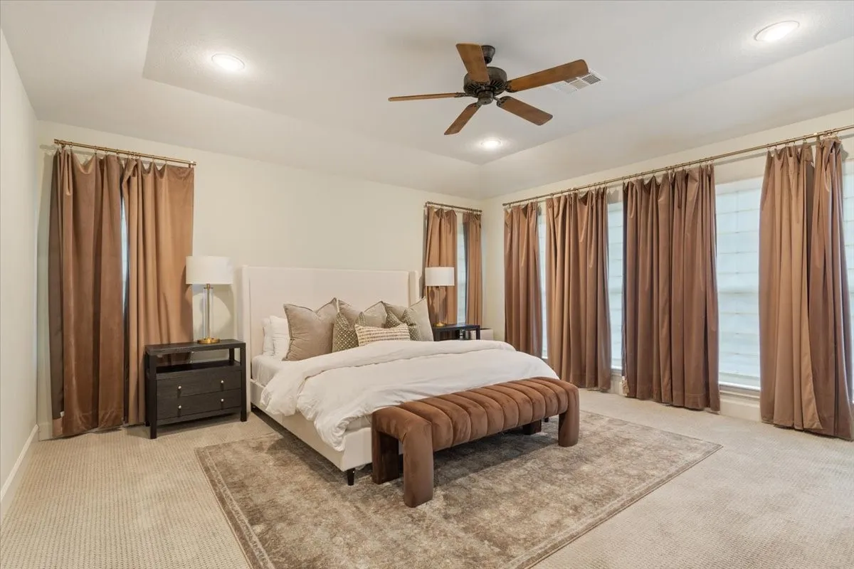 Spacious upstairs primary suite with tray ceiling, recessed lighting, and a five-blade ceiling fan