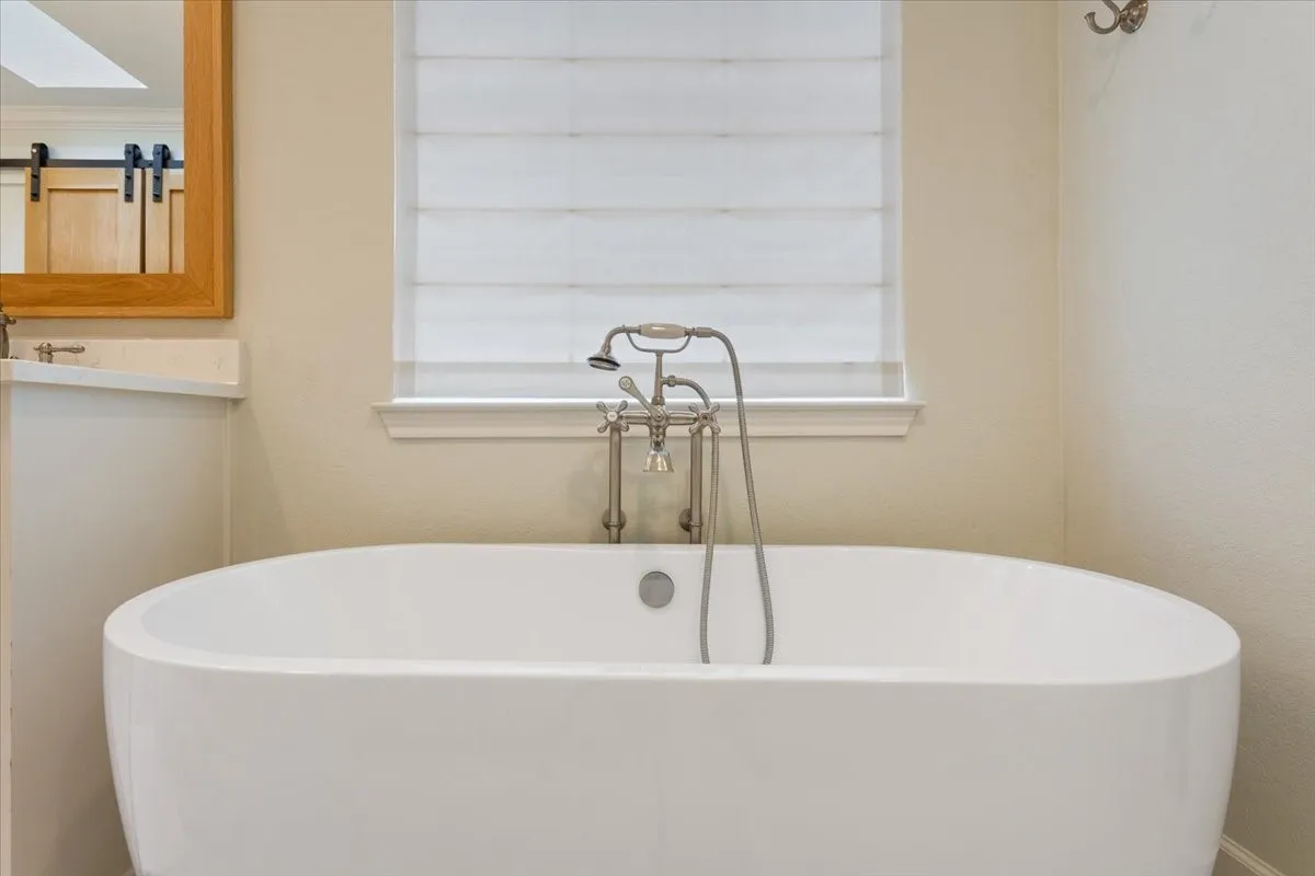 Upstairs freestanding soaking tub with brushed nickel floor-mounted faucet and handheld shower