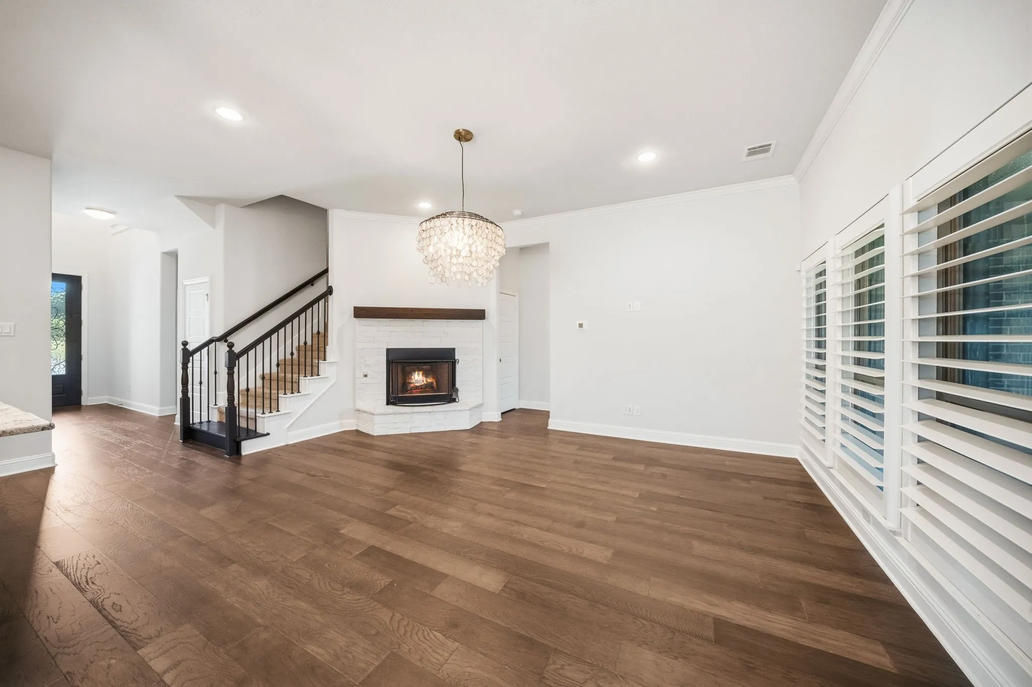 Living area featuring wood-finish flooring, a corner fireplace with a wood mantle, and a crystal​​‌​​​​‌​​‌‌​‌‌​​​‌‌​‌​‌​‌​​​‌​​ chandelier