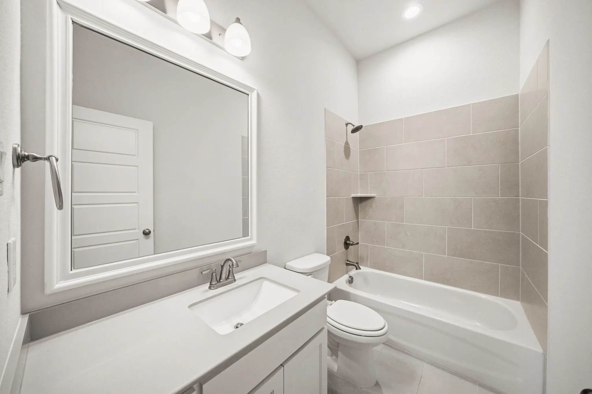 Bathroom featuring a vanity with an integrated sink, a rectangular mirror, and a wall-mounted light fixture