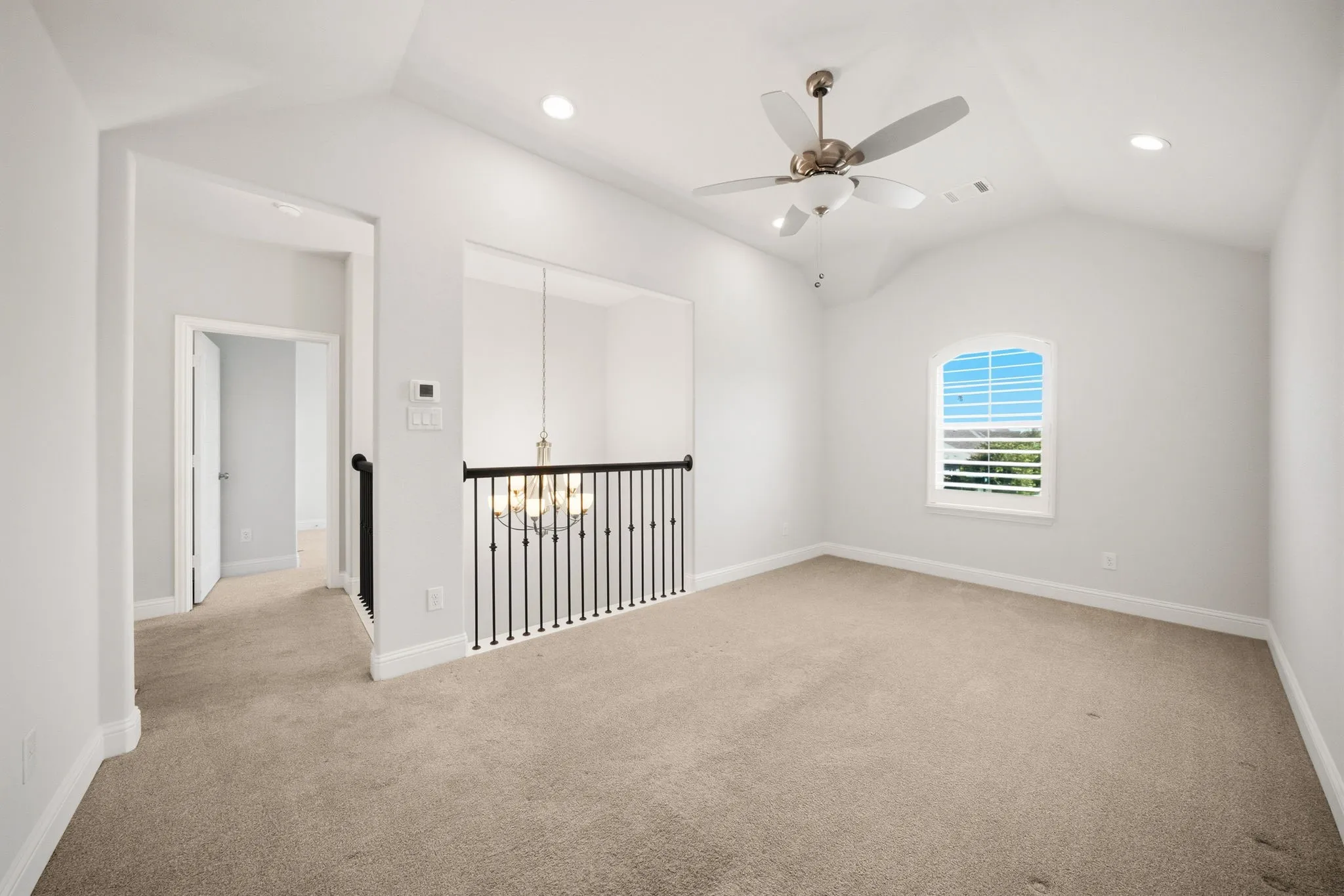 Upstairs Living Room featuring a vaulted ceiling with a ceiling fan, recessed lighting, an arched window with plantation shutters, and black iron baluster railing
