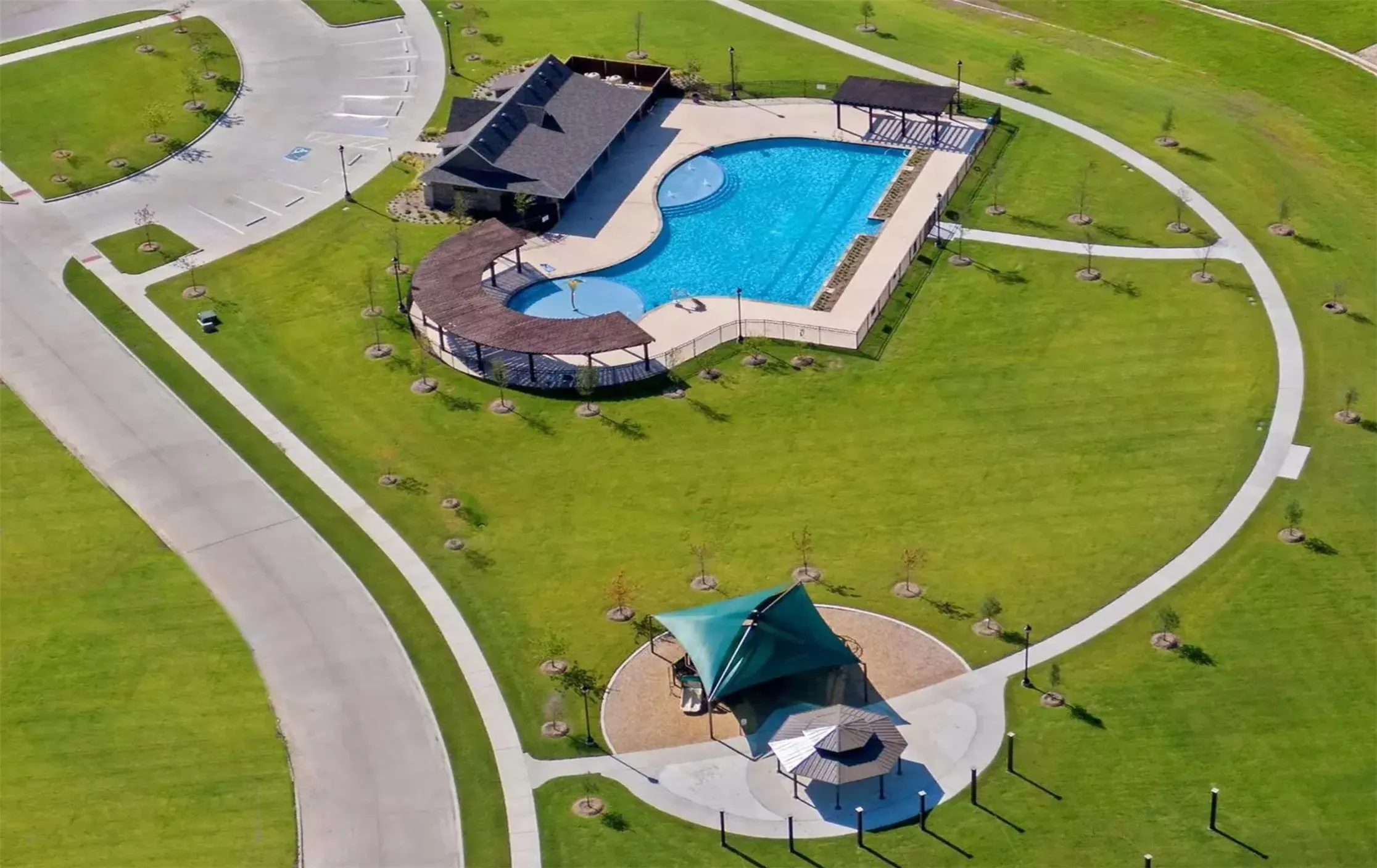 Community recreation area featuring a large swimming pool, a separate children's splash pad, and an adjacent building with covered patio