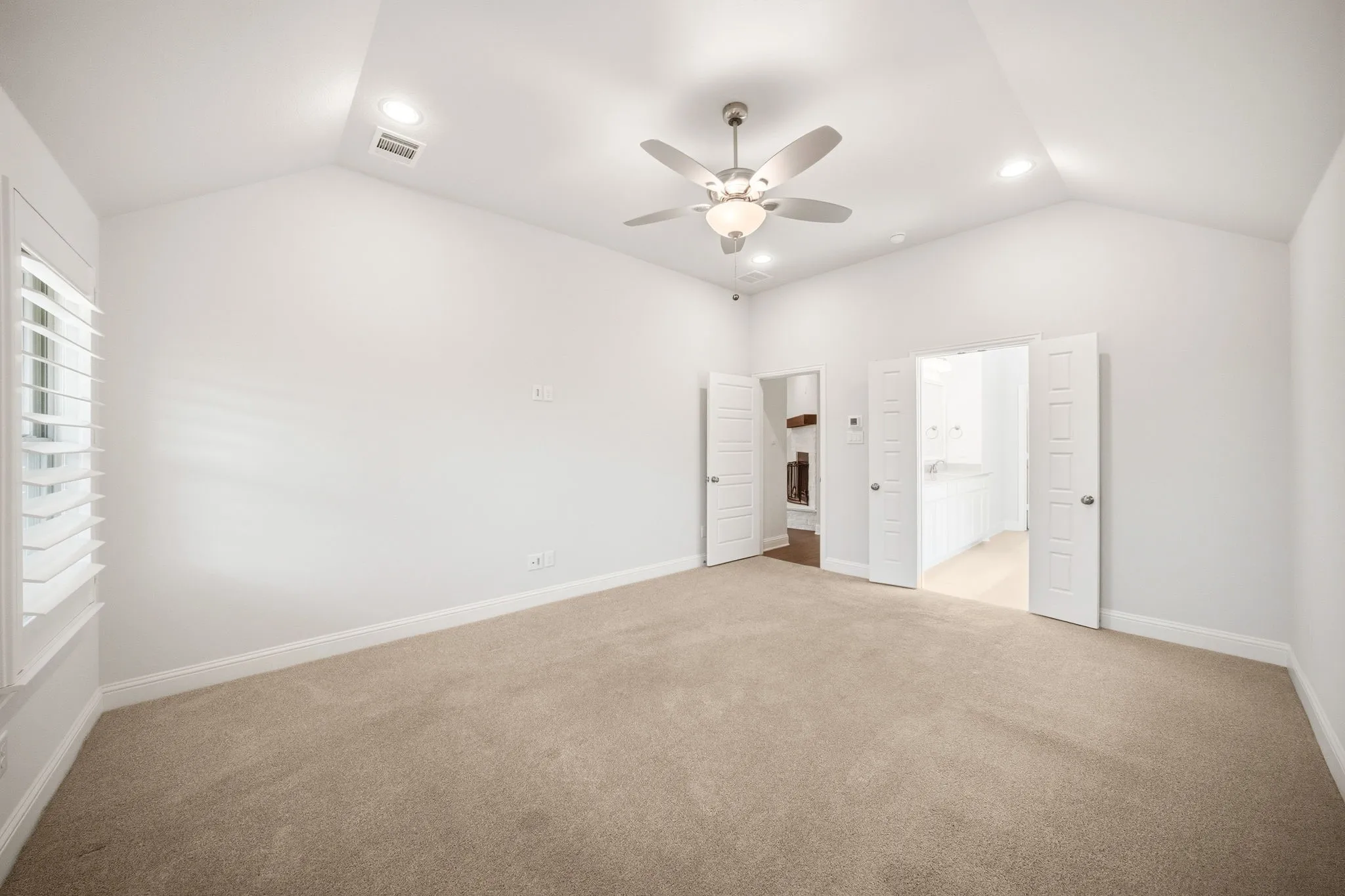 Spacious room featuring vaulted ceilings with recessed lighting, a ceiling fan, and plush carpet flooring