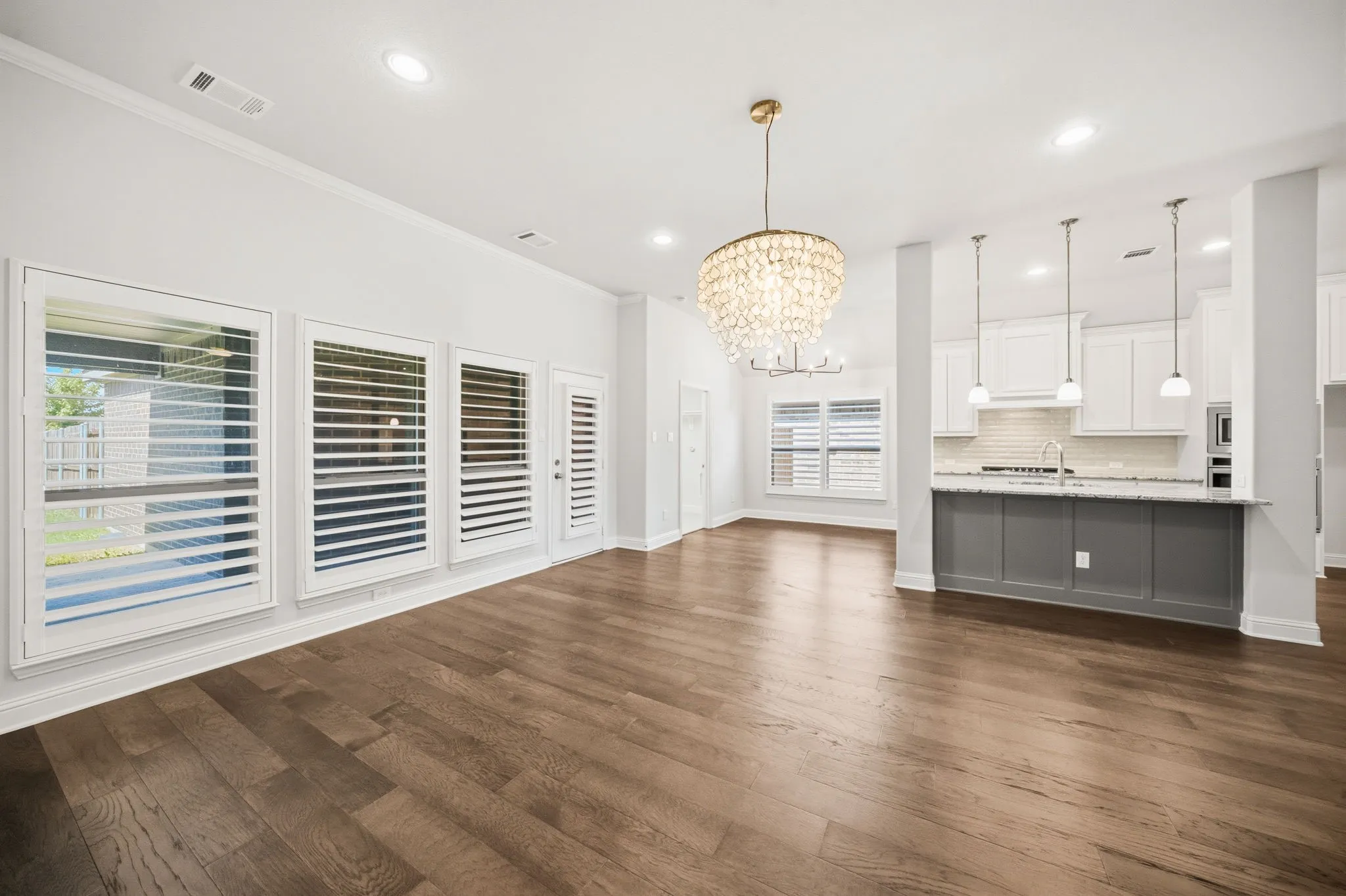 Open concept living space featuring wood-finish flooring, a crystal chandelier, and recessed lighting
