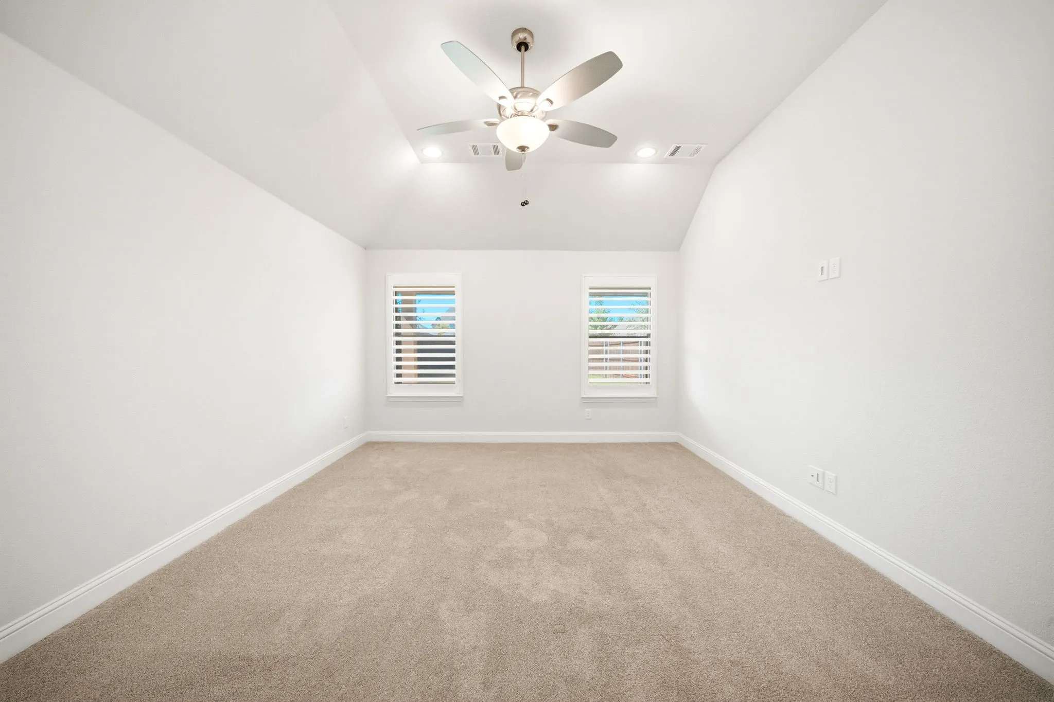 Vaulted ceiling with a brushed nickel ceiling fan and recessed lighting