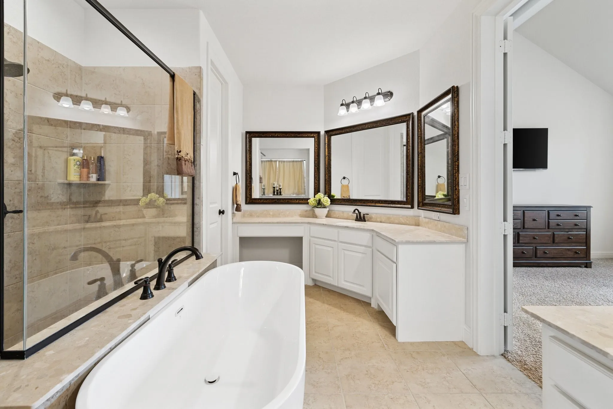 Bathroom featuring a freestanding tub, glass-enclosed shower with tile surround, and a double vanity with built-in cabinetry