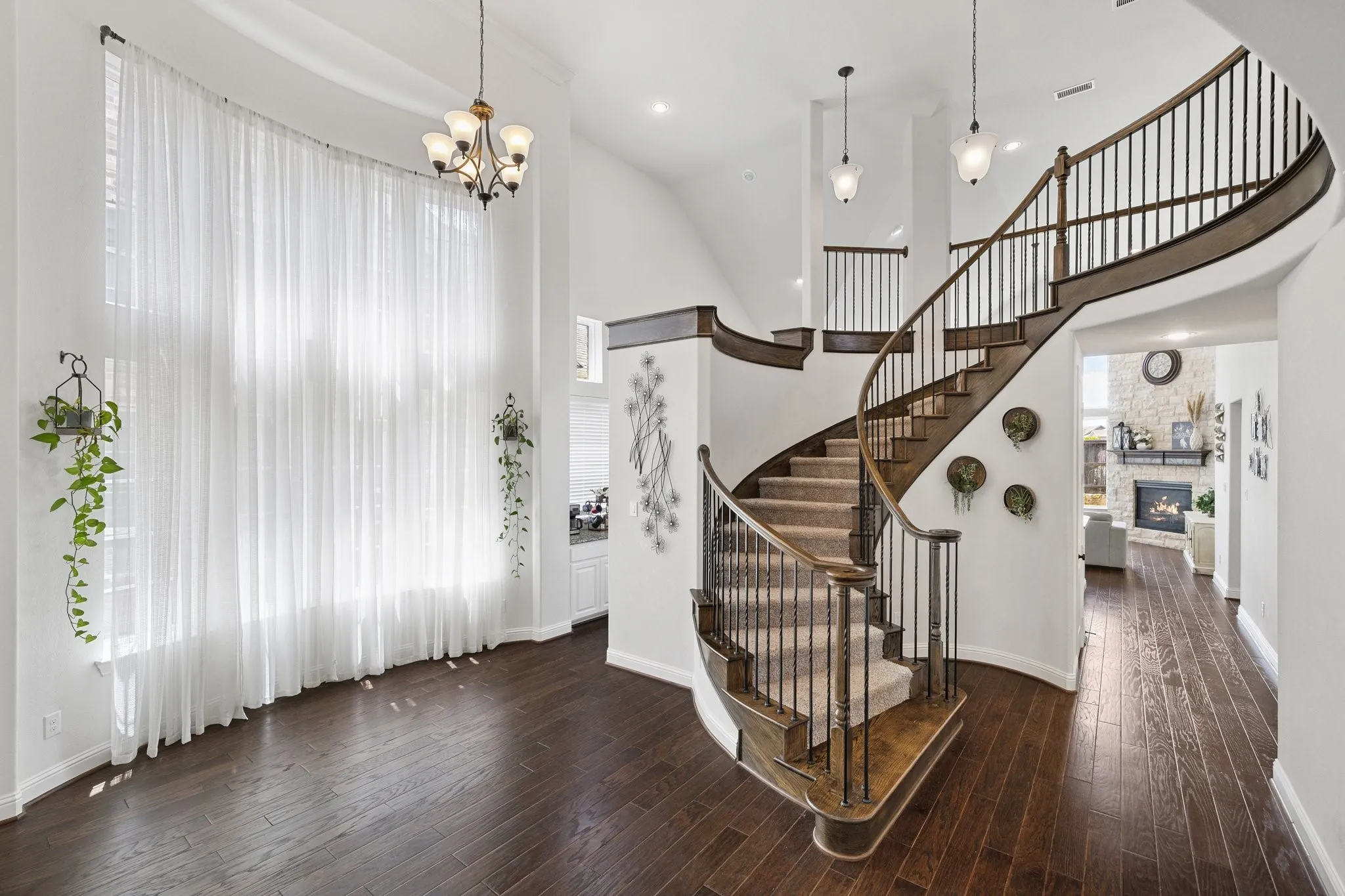 Sweeping spiral staircase with wrought iron balusters and wood-finish handrails