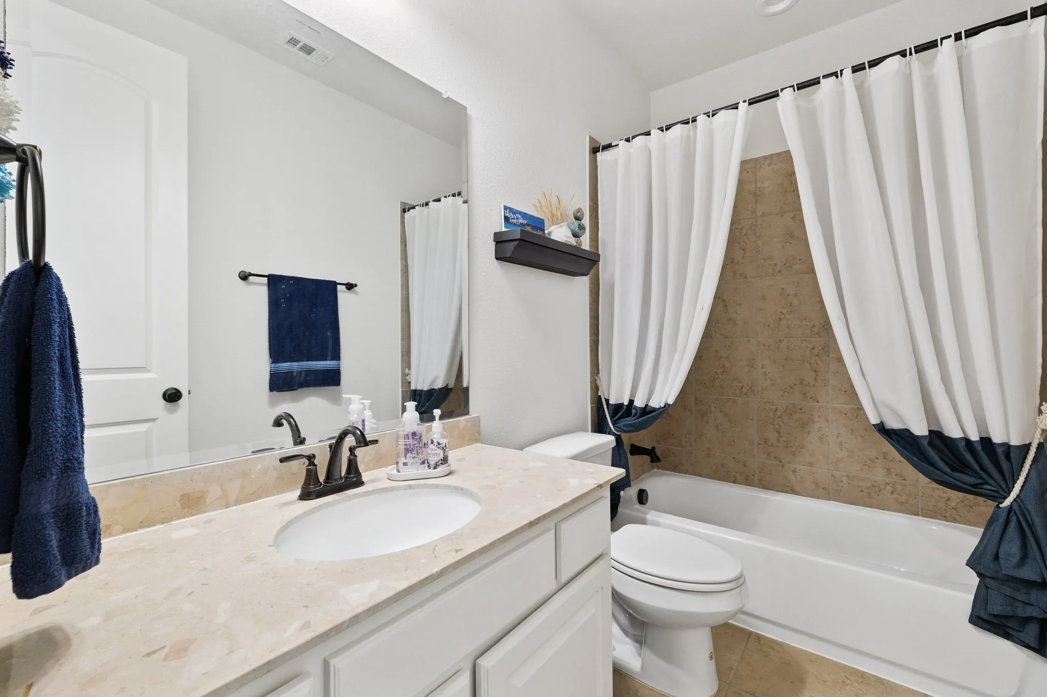 Bathroom featuring a single vanity with a light-toned countertop, undermount sink, and bronze-finish faucet