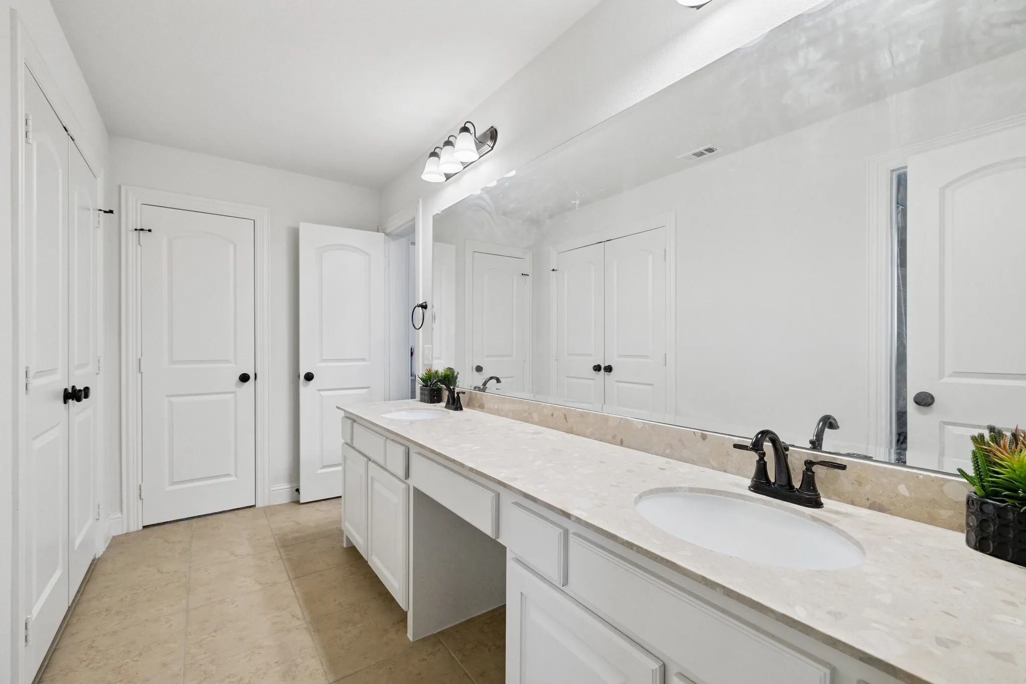 Dual vanity with inset sinks, stone countertops, and dark bronze fixtures