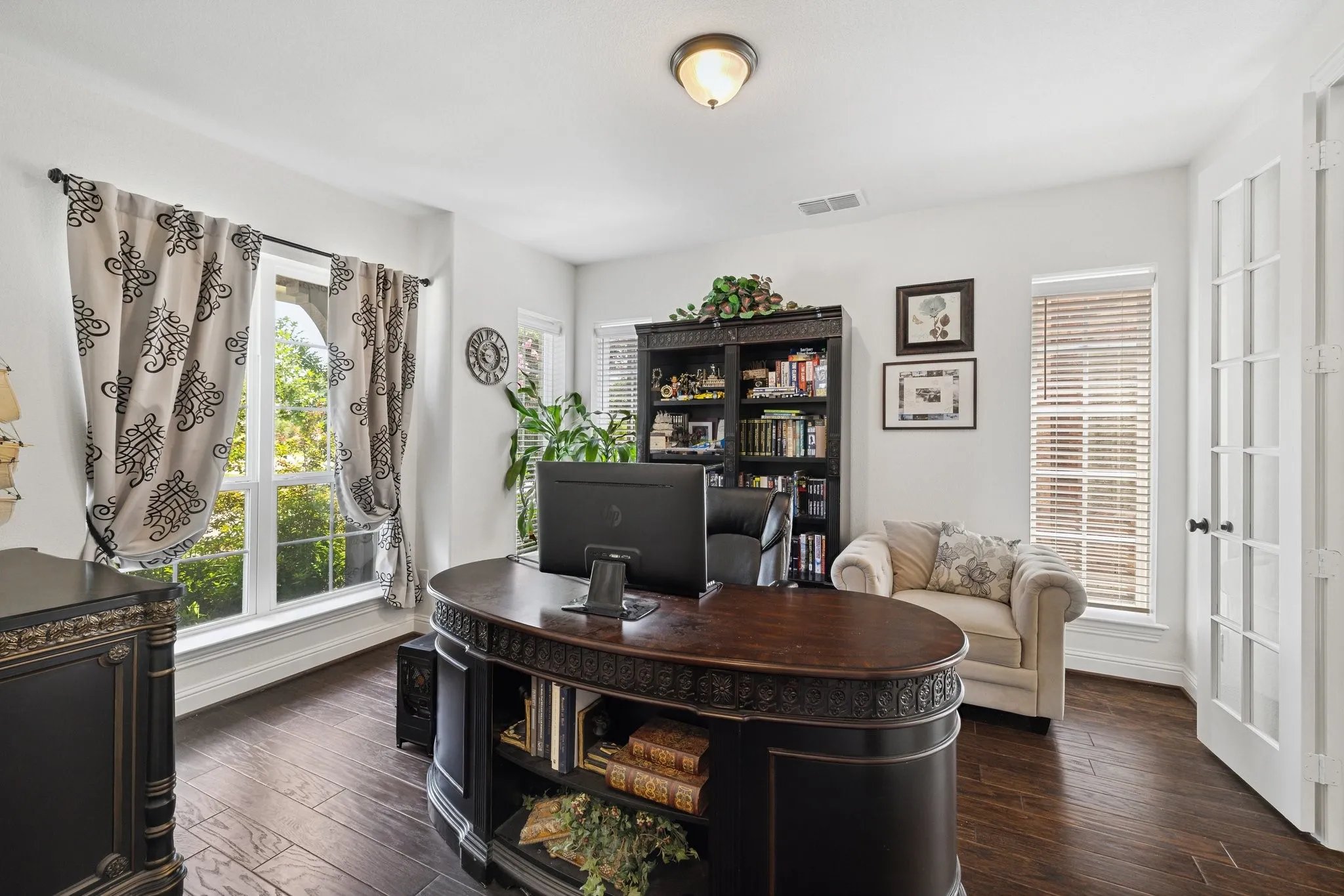 Dedicated room featuring wood-finish flooring, a large picture window, and a pair of white French doors