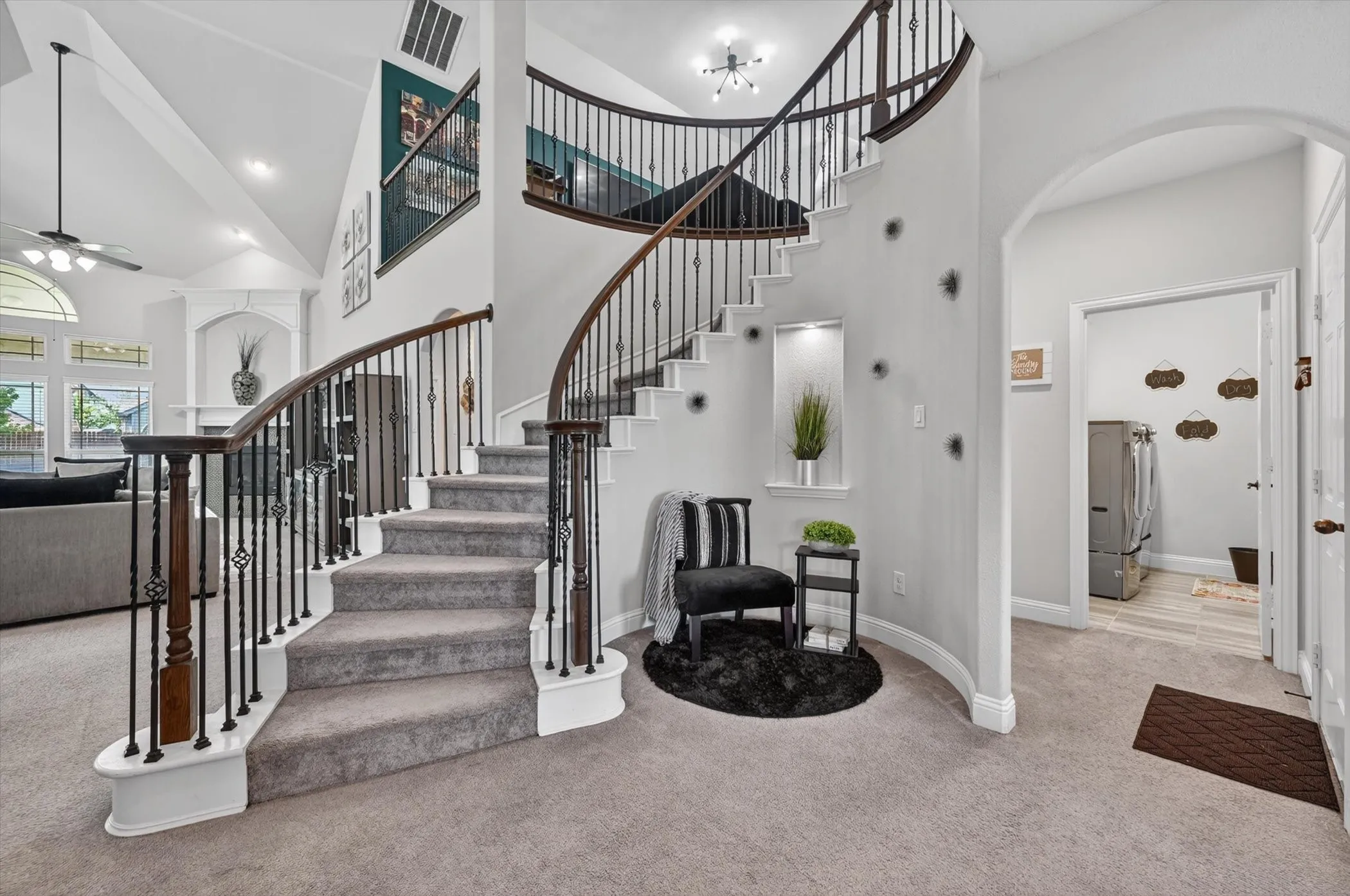 Elegant curved staircase featuring dark wood handrails and black wrought iron balusters