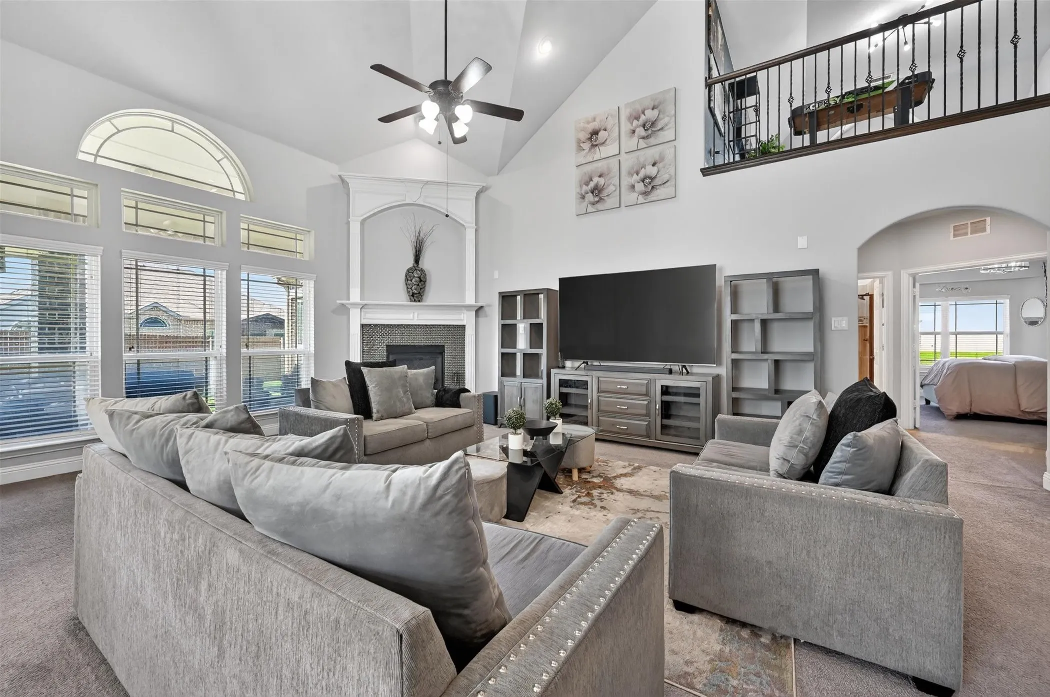 Spacious living area featuring a vaulted ceiling and an ornate fireplace mantel