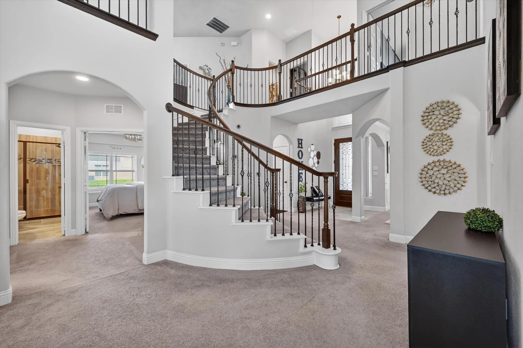 Grand foyer with a curved staircase featuring dark wood handrails and wrought iron balusters