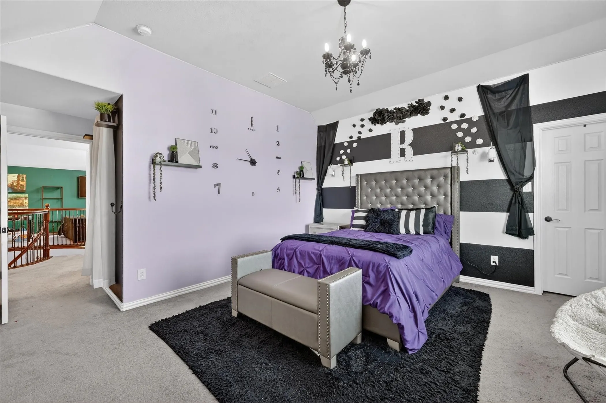 Carpeted bedroom featuring a black and white accent wall with sconce lighting, a tufted headboard, and an attached chandelier
