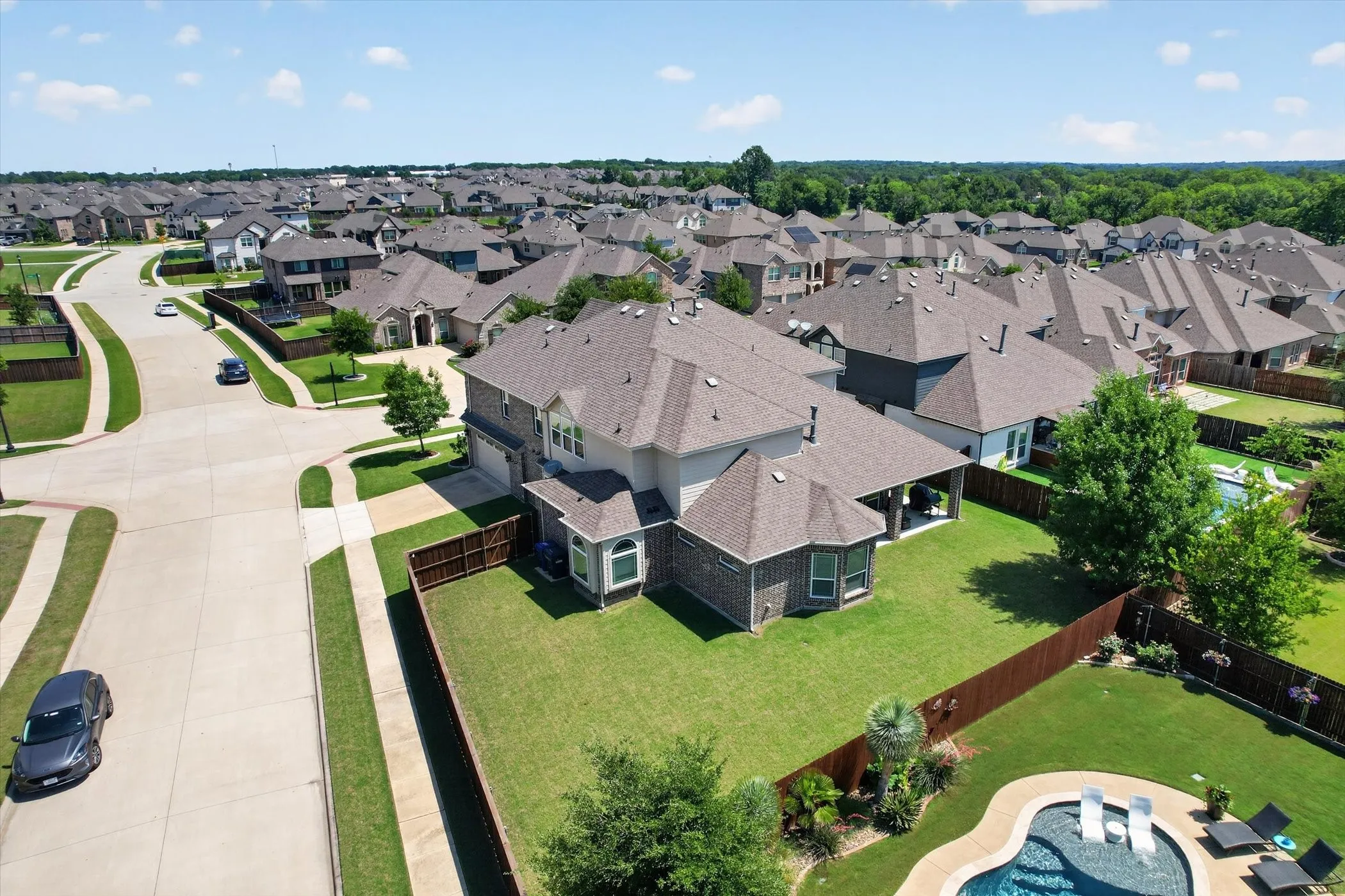 Aerial perspective of a contemporary two-story residence featuring a brick and siding exterior and a multi-gabled roofline