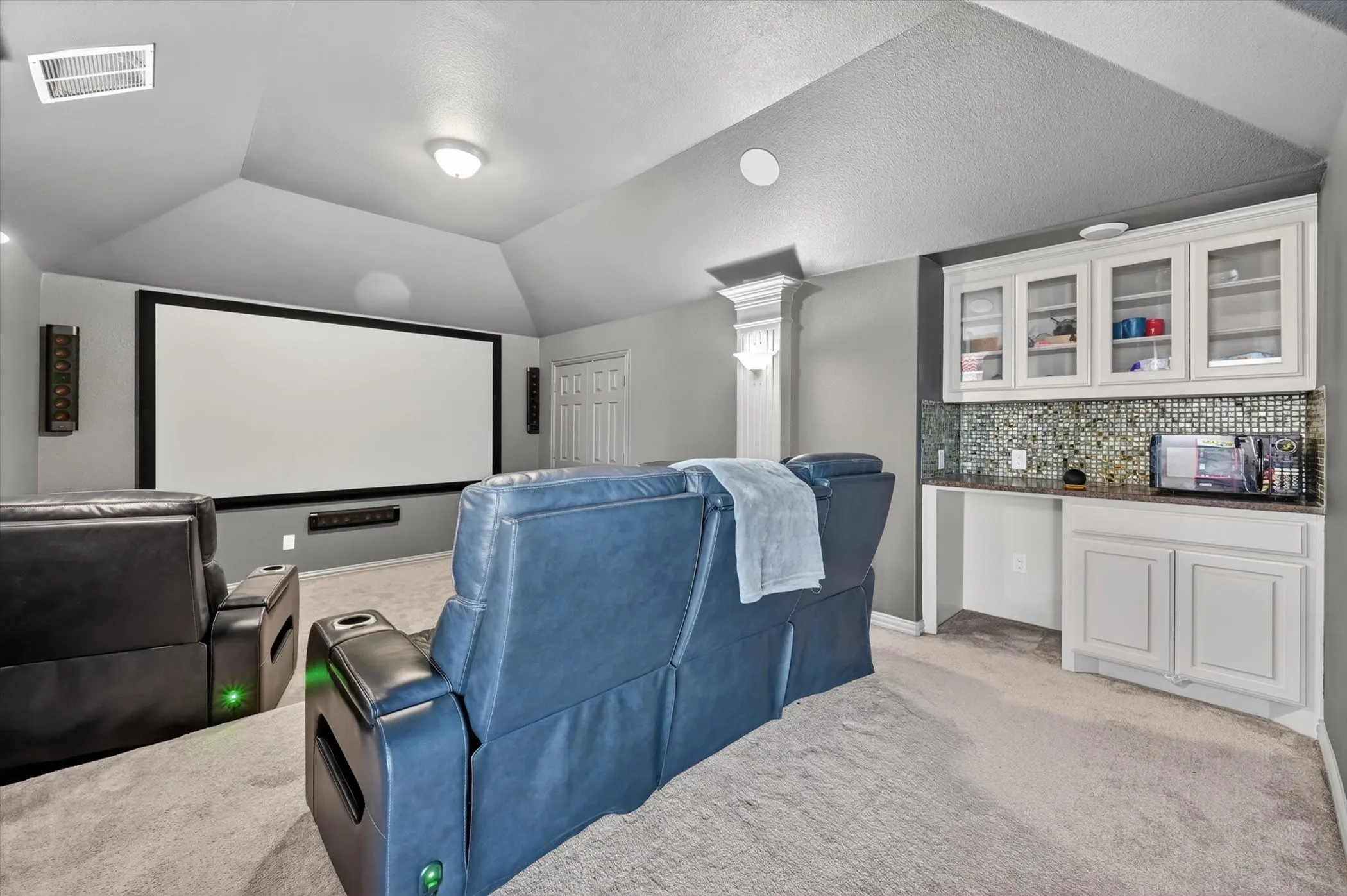 Dedicated media room featuring a large projection screen, built-in sound system, and recessed lighting