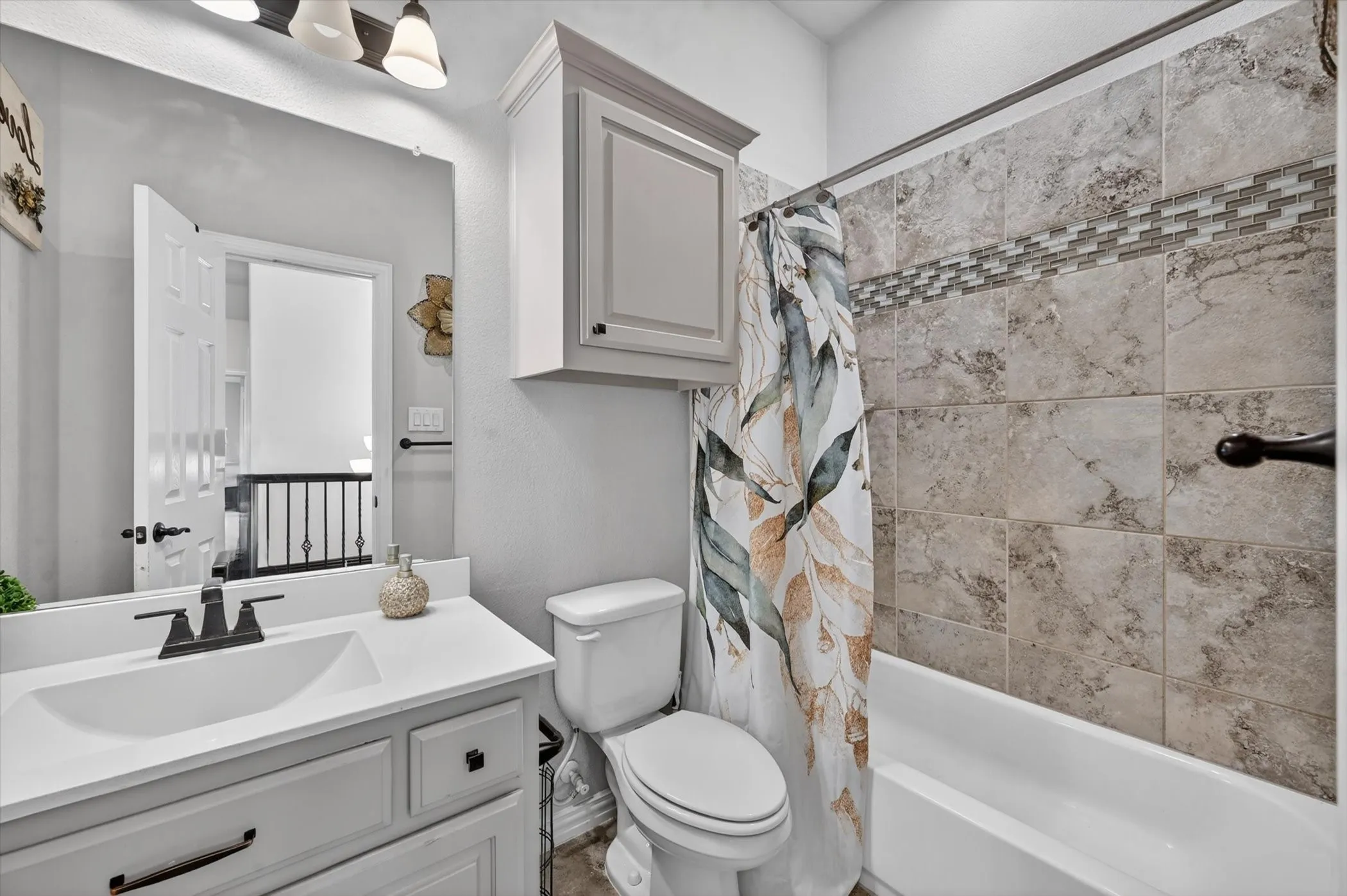 Full bathroom featuring a single vanity with a white countertop and undermount sink, matte black faucet, and a shower/tub combination with a tiled surround