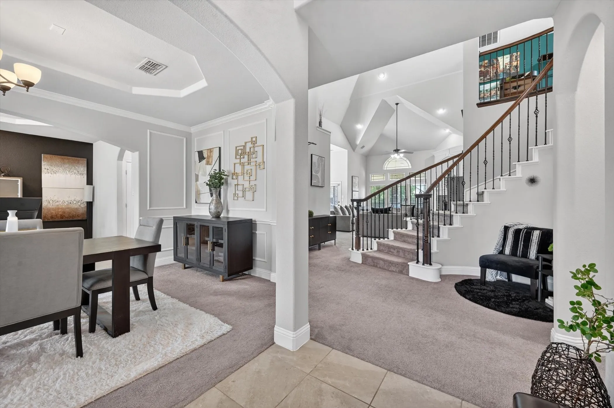 Entryway featuring a grand staircase with wrought iron balusters and wood handrails, vaulted ceilings, and recessed lighting