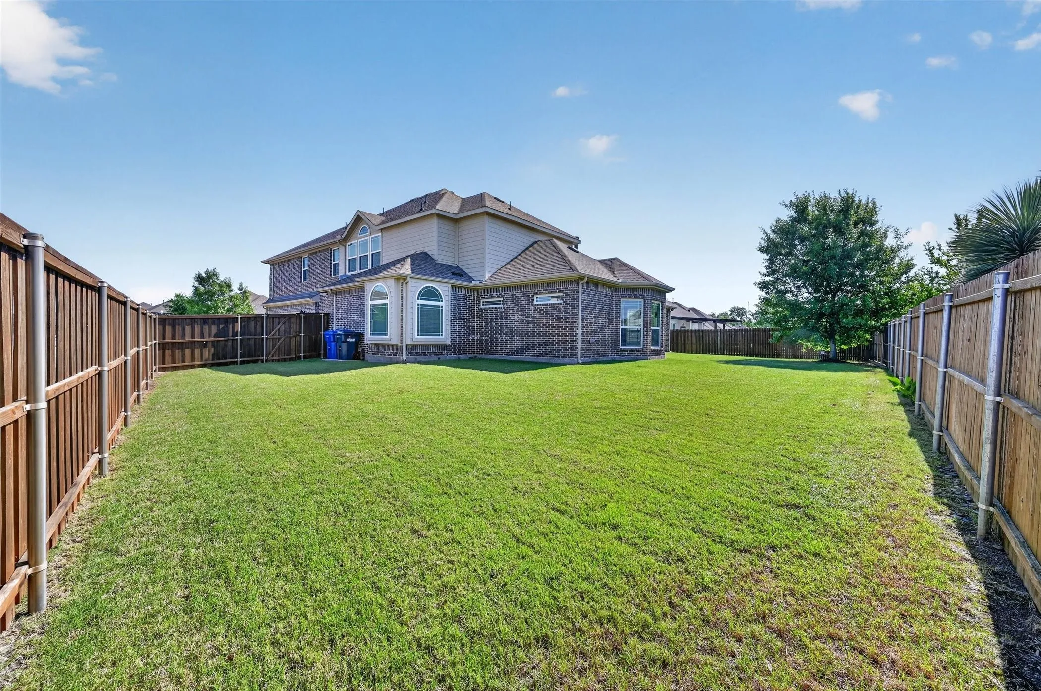 Expansive green lawn with a full privacy fence