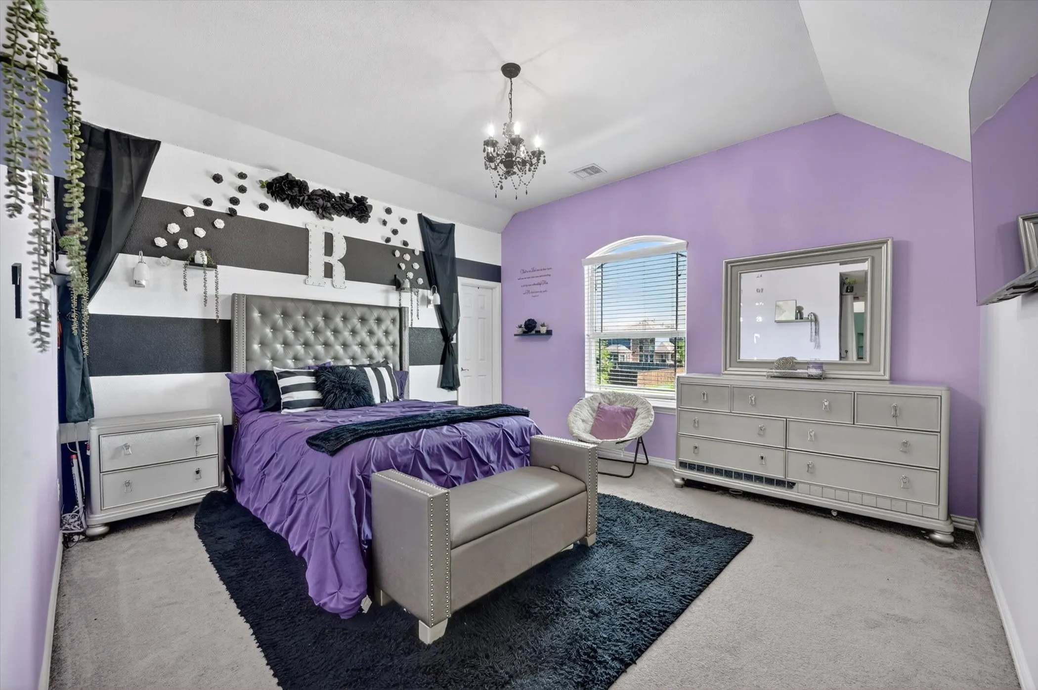 Vaulted ceiling bedroom featuring a chandelier light fixture, arched window with horizontal blinds, and carpeted flooring
