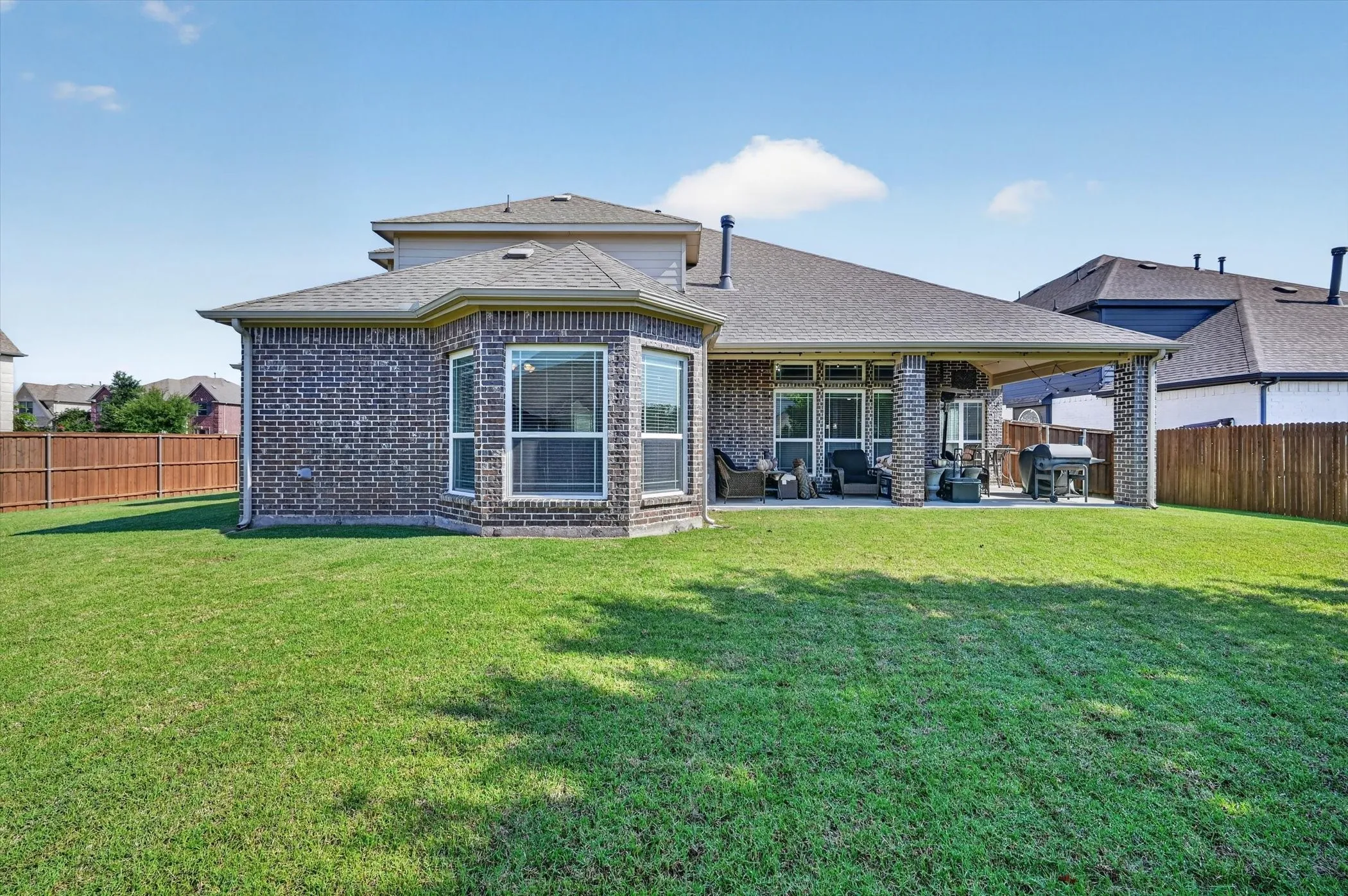 Expansive rear yard featuring a large covered patio and a separate bay window extension