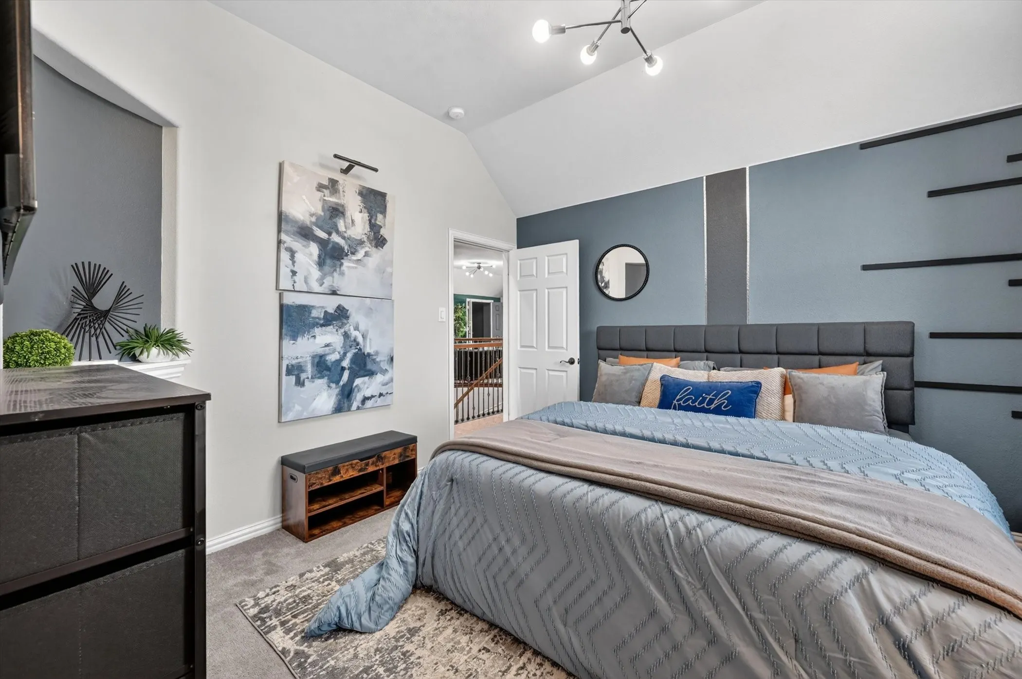 Vaulted ceiling bedroom with accent wall detailing, plush carpeting, and contemporary lighting fixture