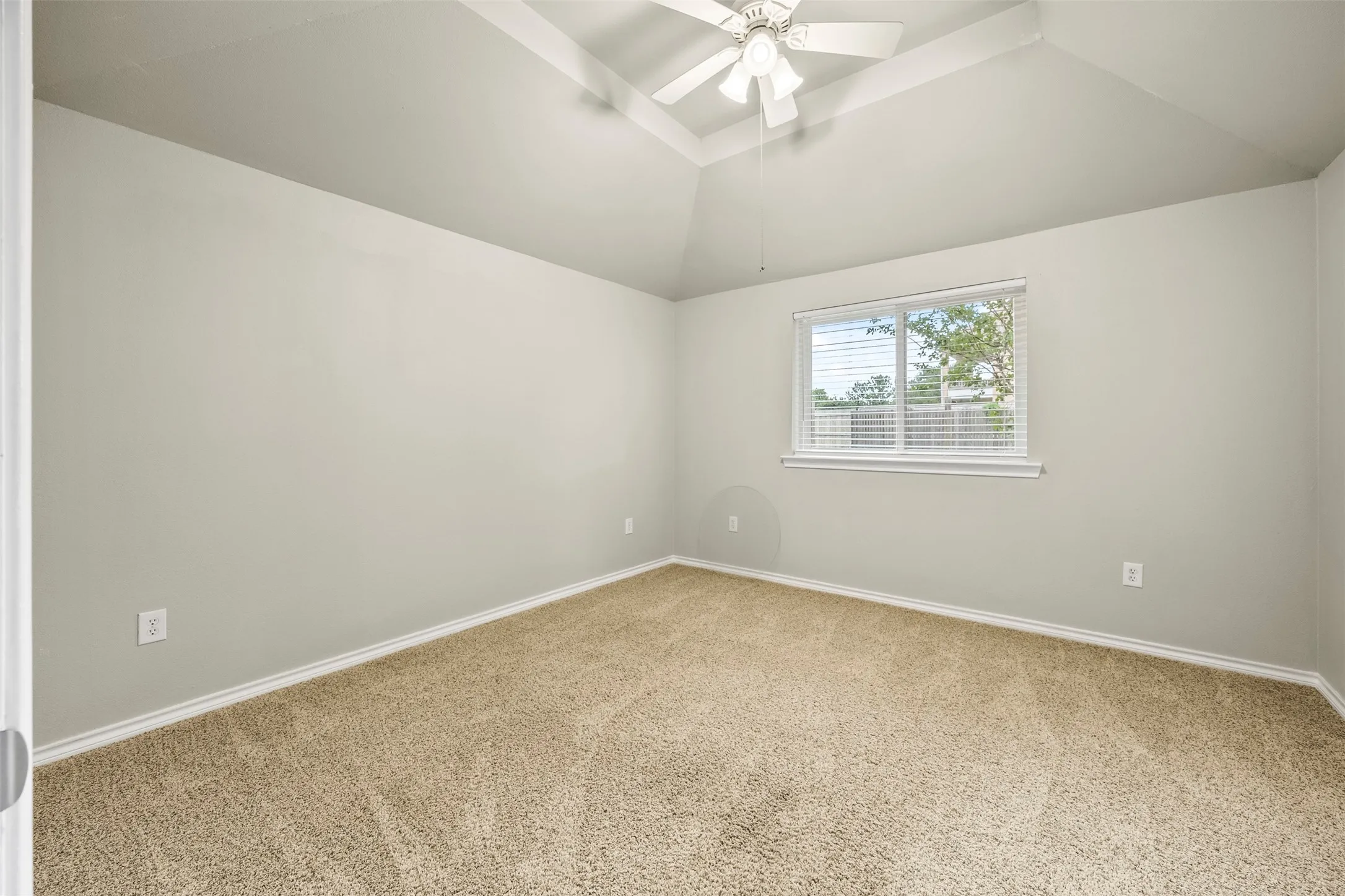 Carpeted interior space featuring a vaulted ceiling and a ceiling fan