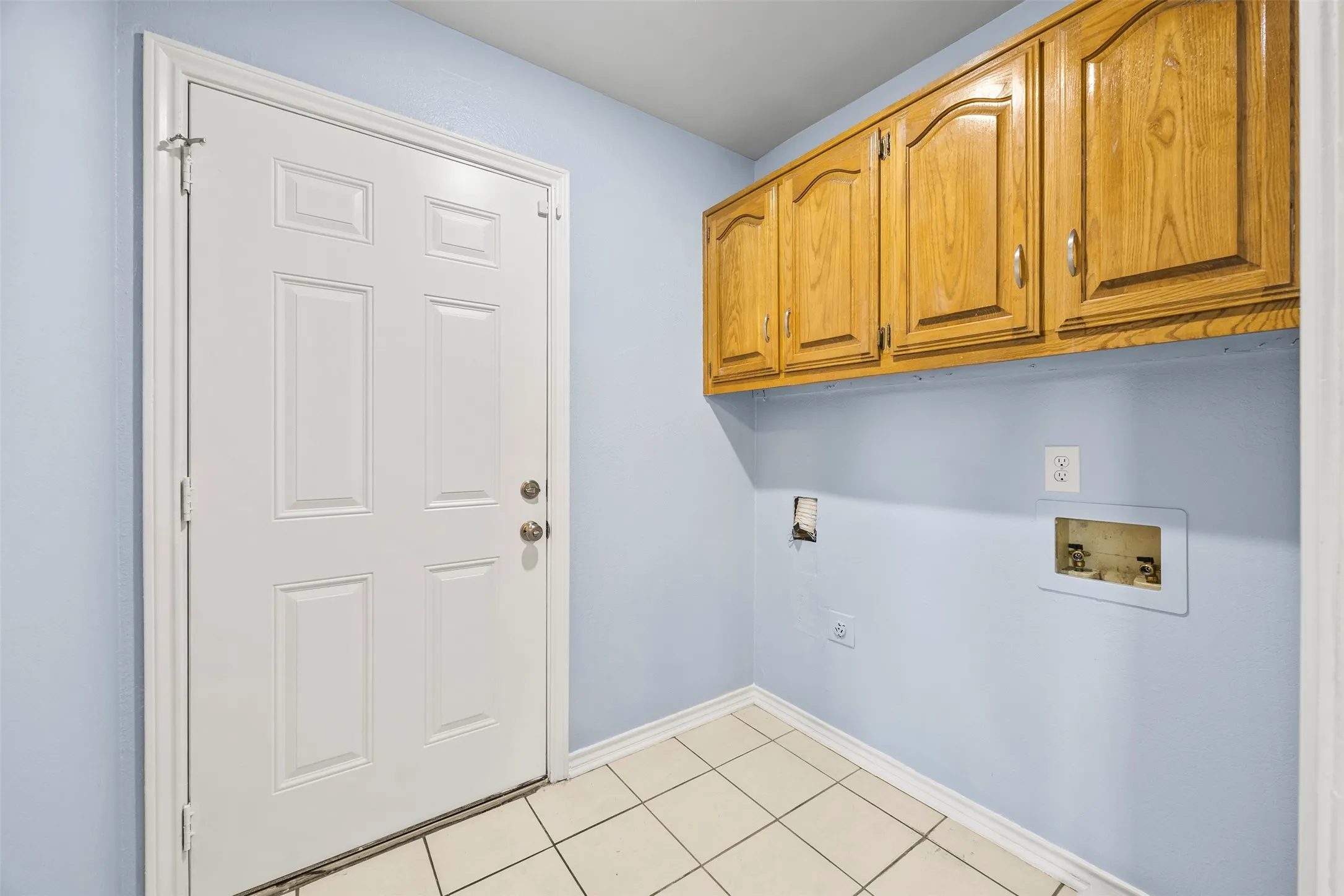 Utility area with tiled flooring, light blue walls, and a white paneled door