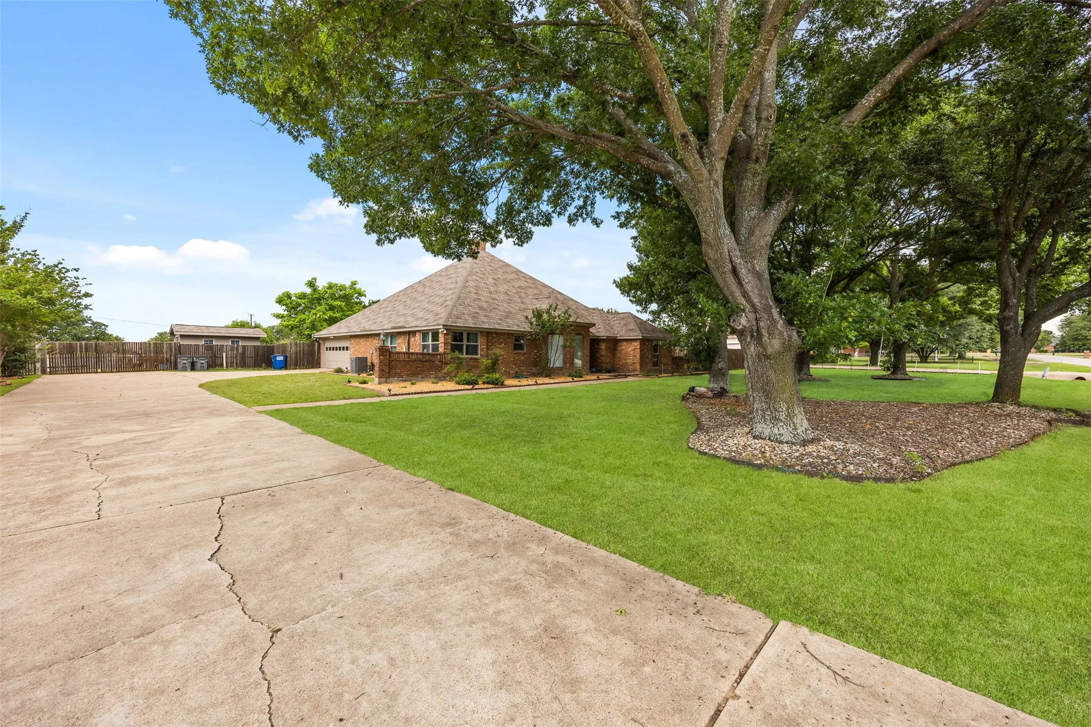 Expansive concrete driveway bordering a manicured lawn with mature trees