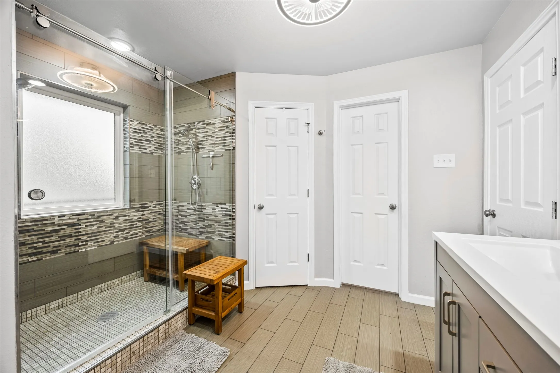 Walk-in shower with glass enclosure, textured tile surround, and frosted window